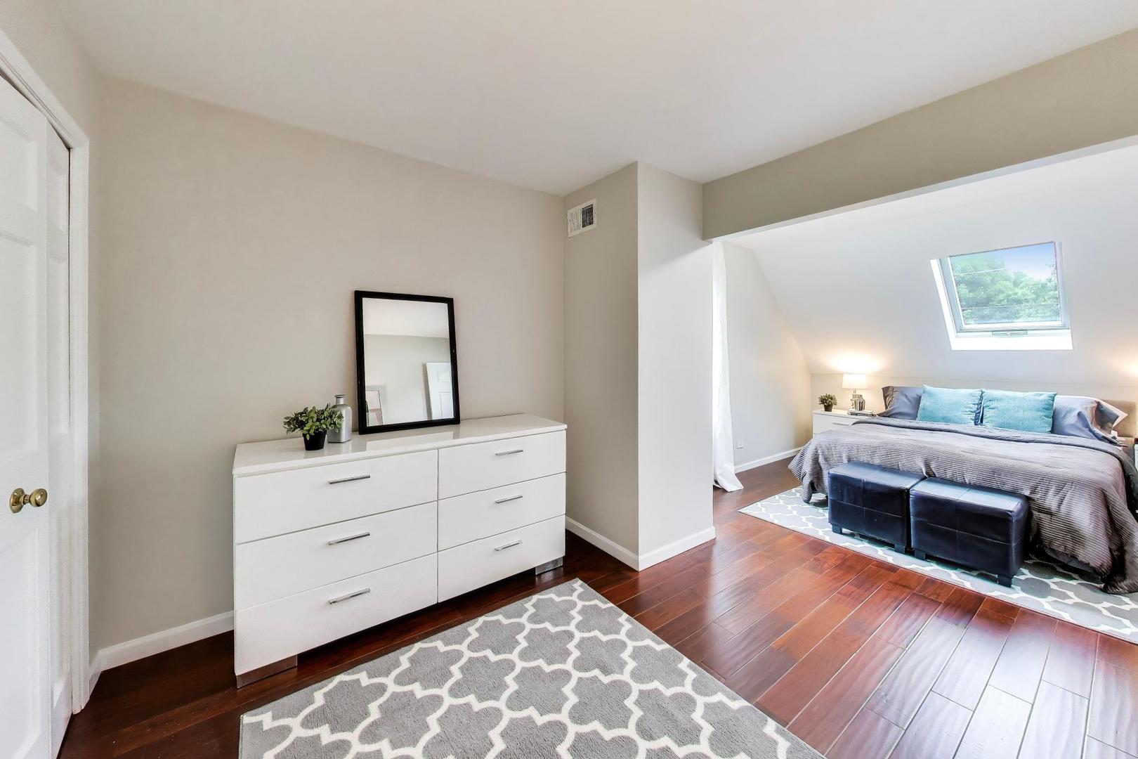 Bedroom with a skylight, sloped ceiling, dark hardwood floors, and white dresser.