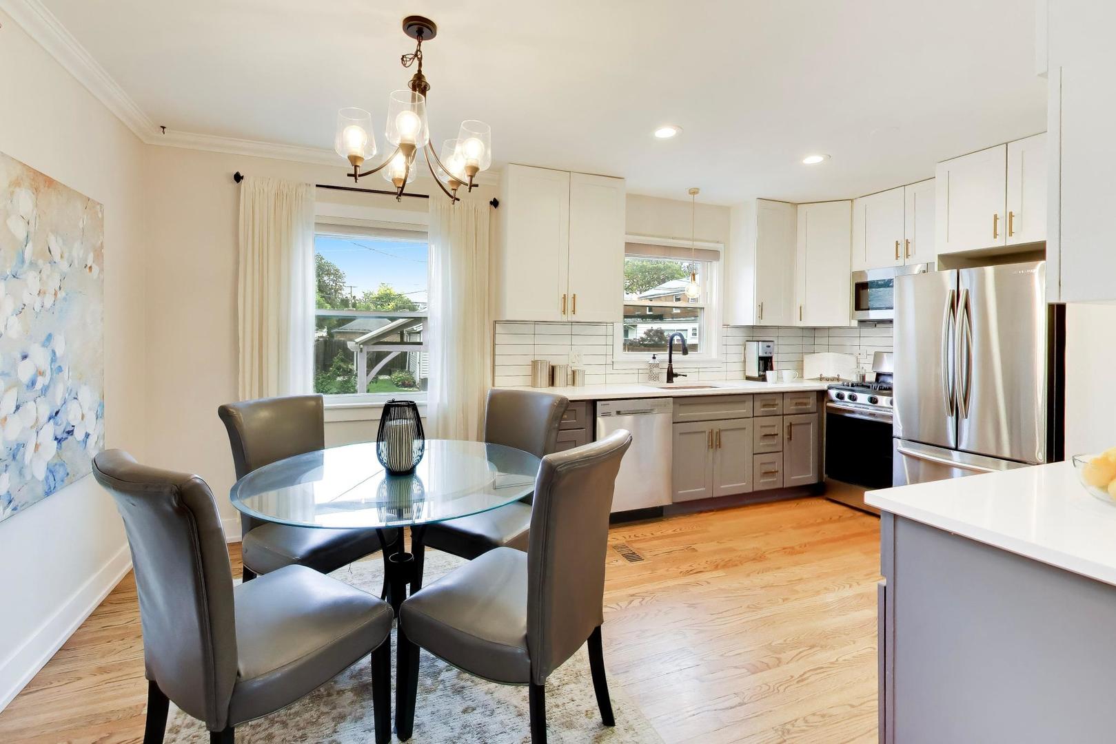 Kitchen and dining area with white cabinets, stainless steel appliances, and a glass dining table.