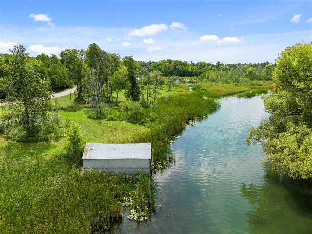 Aerial view of a marshy property with a winding waterway and small shed.