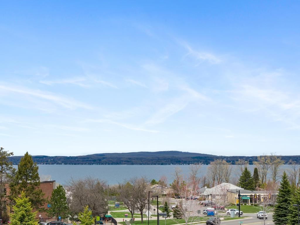 Lakeside town and homes below a wide blue bay and wooded hills.