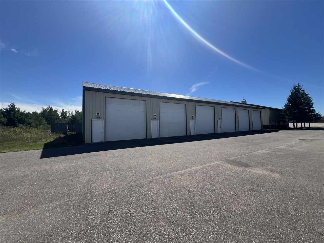 Long gray garage building with multiple bays beside a broad paved lot.