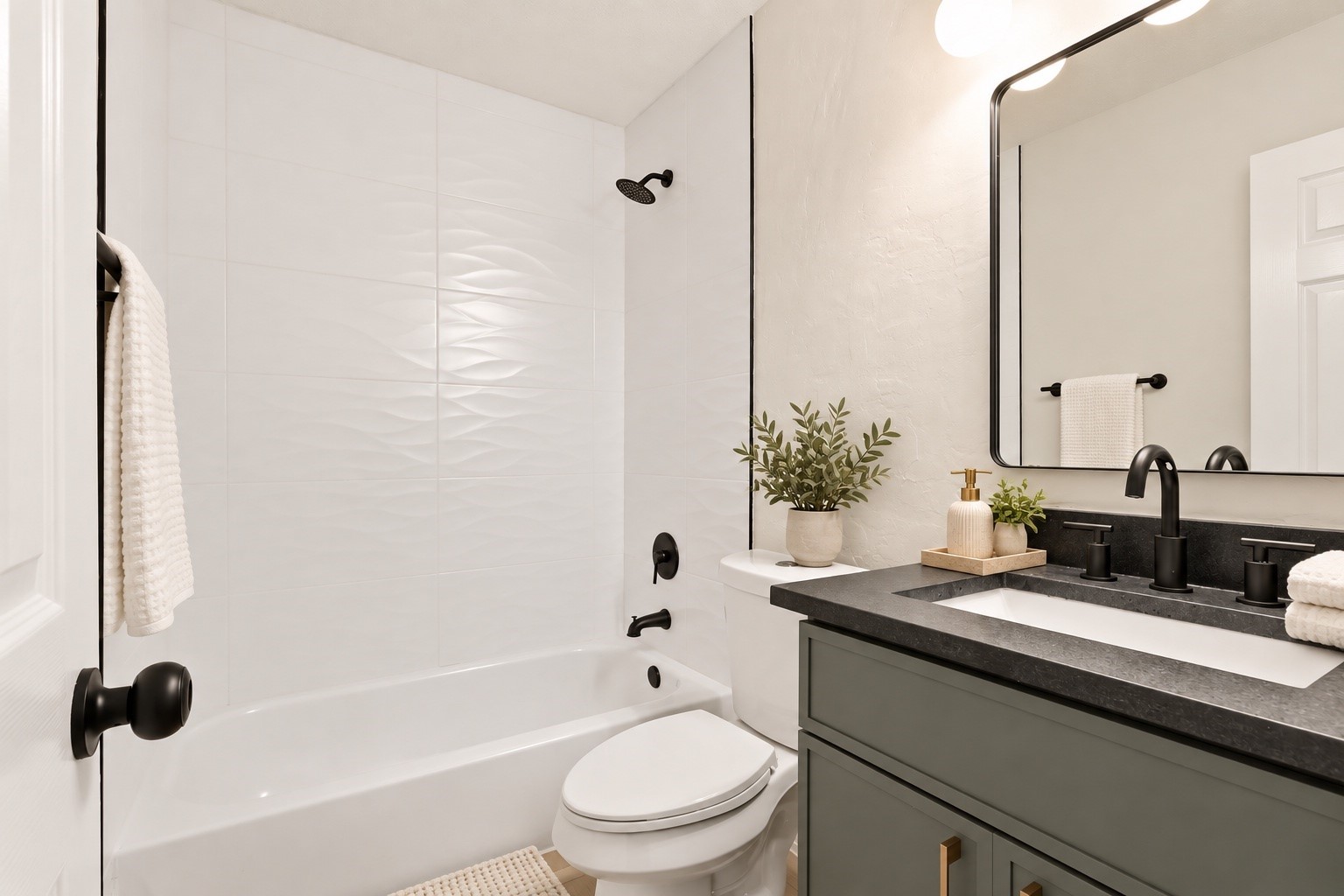 Bathroom with a white tub, textured tile, black fixtures, and a sage-green vanity.
