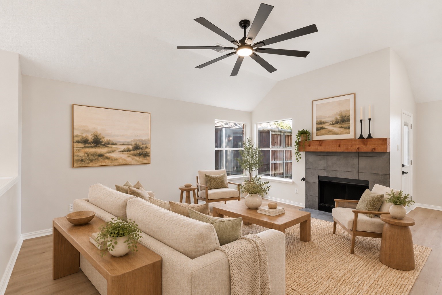 Staged living room with vaulted ceiling, large ceiling fan, and tiled fireplace with wood mantel.