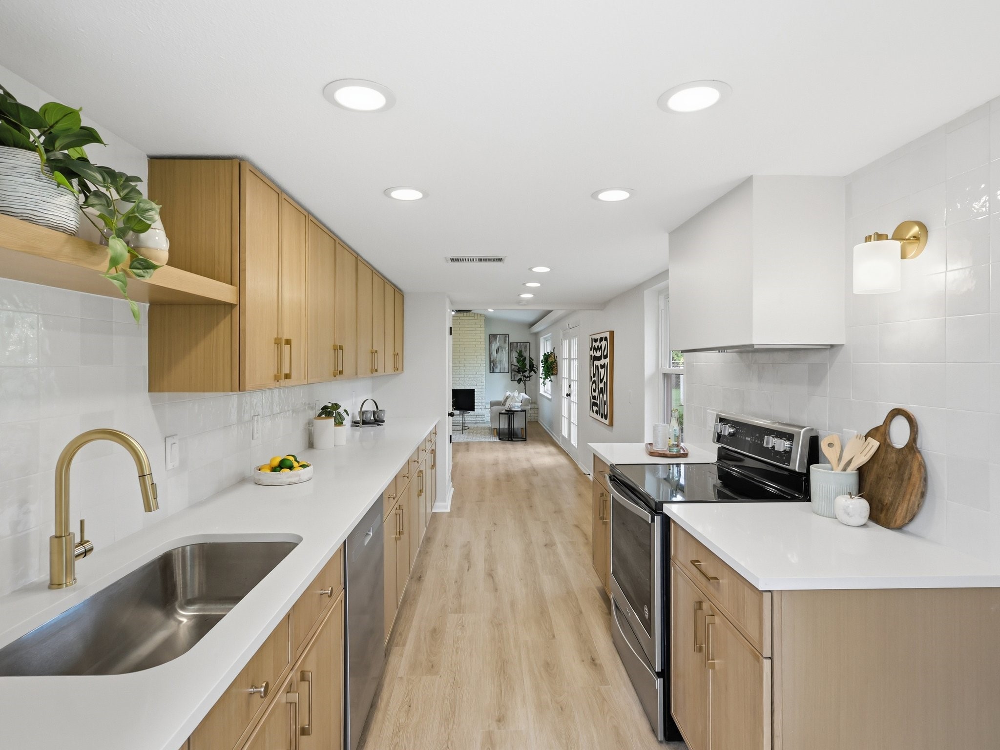 Renovated galley kitchen with light wood cabinets, white counters, and a stainless steel range.