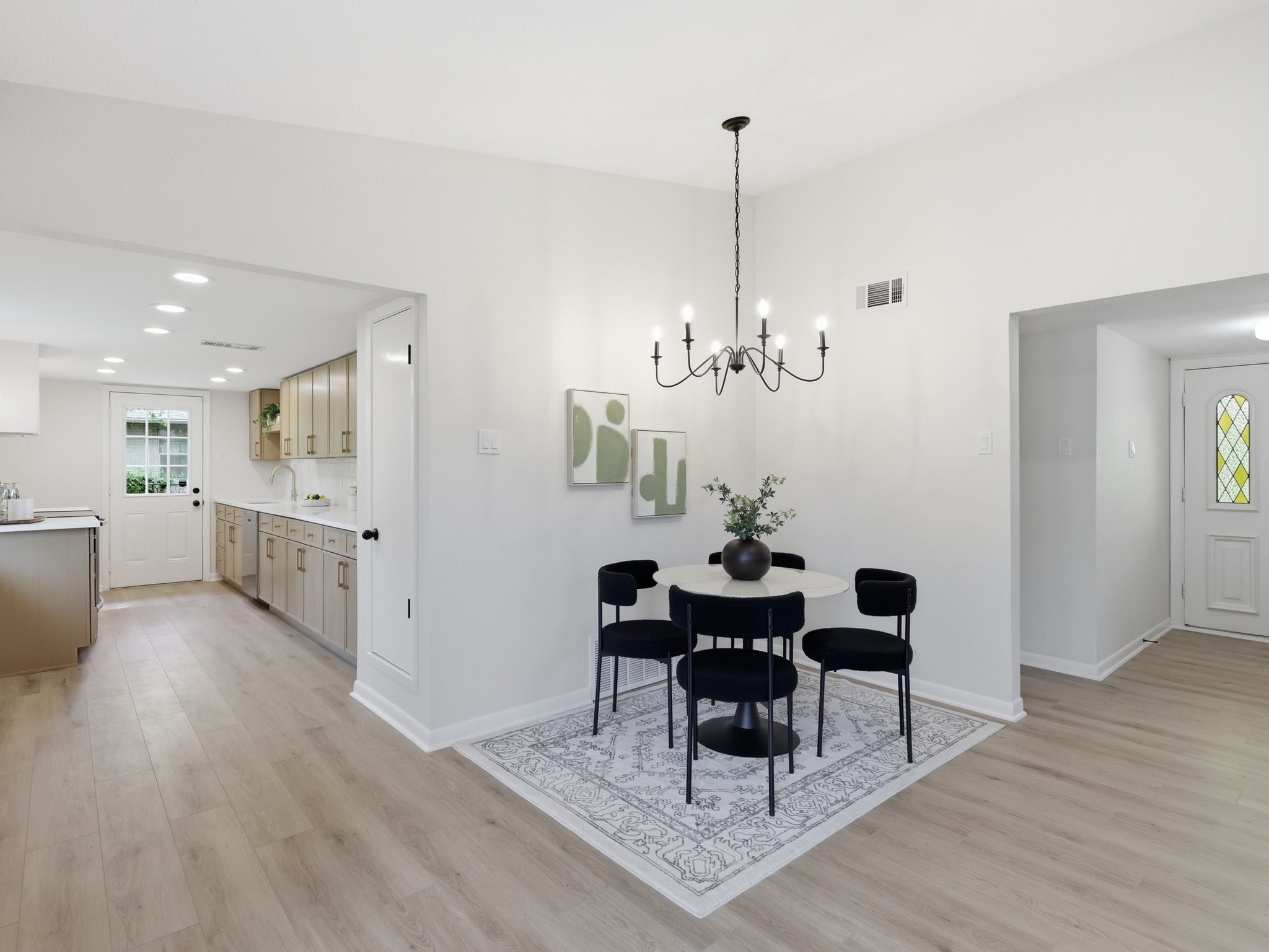 Dining area with a round table and dark chairs beside an open kitchen.