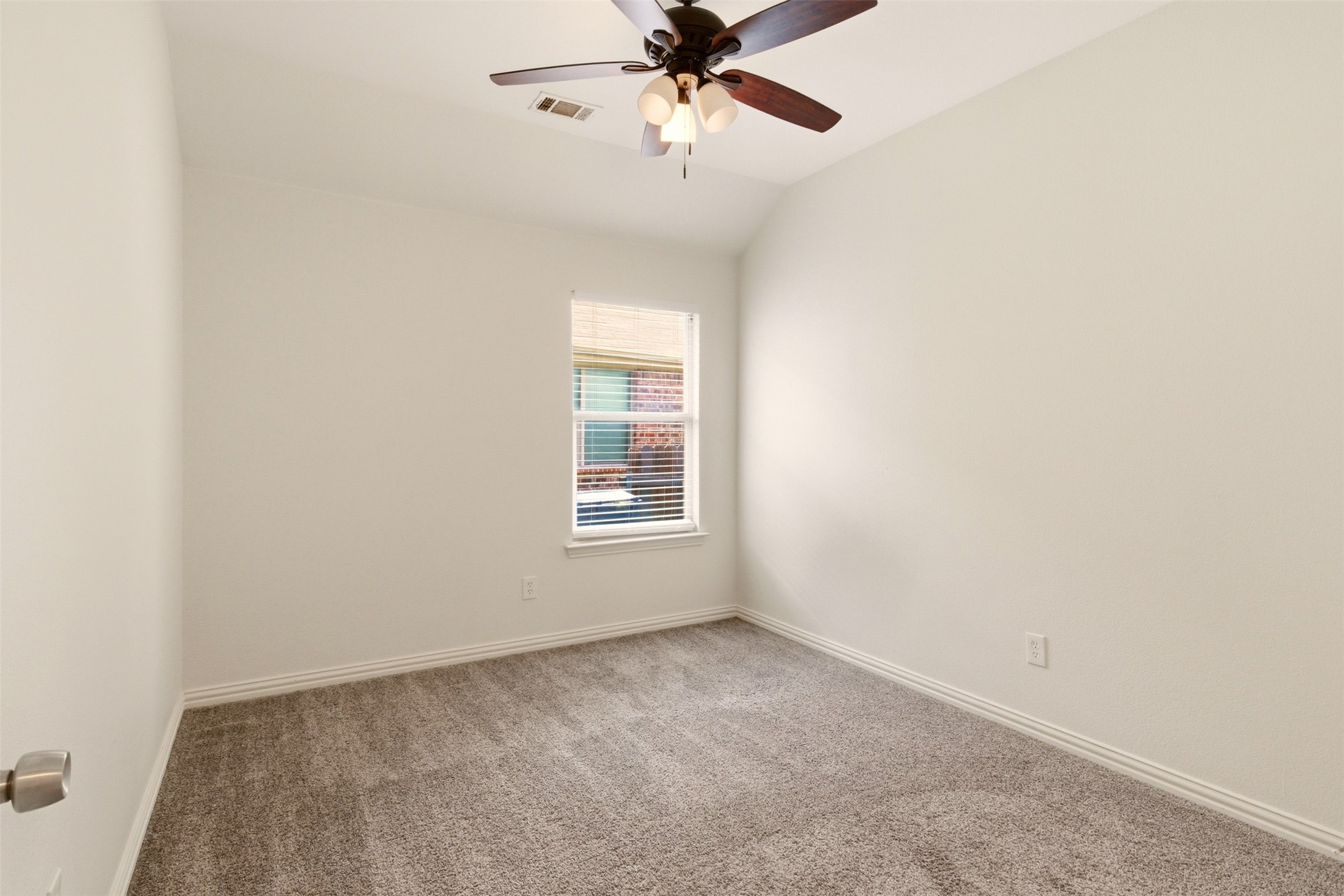 Empty carpeted bedroom with a window and ceiling fan.