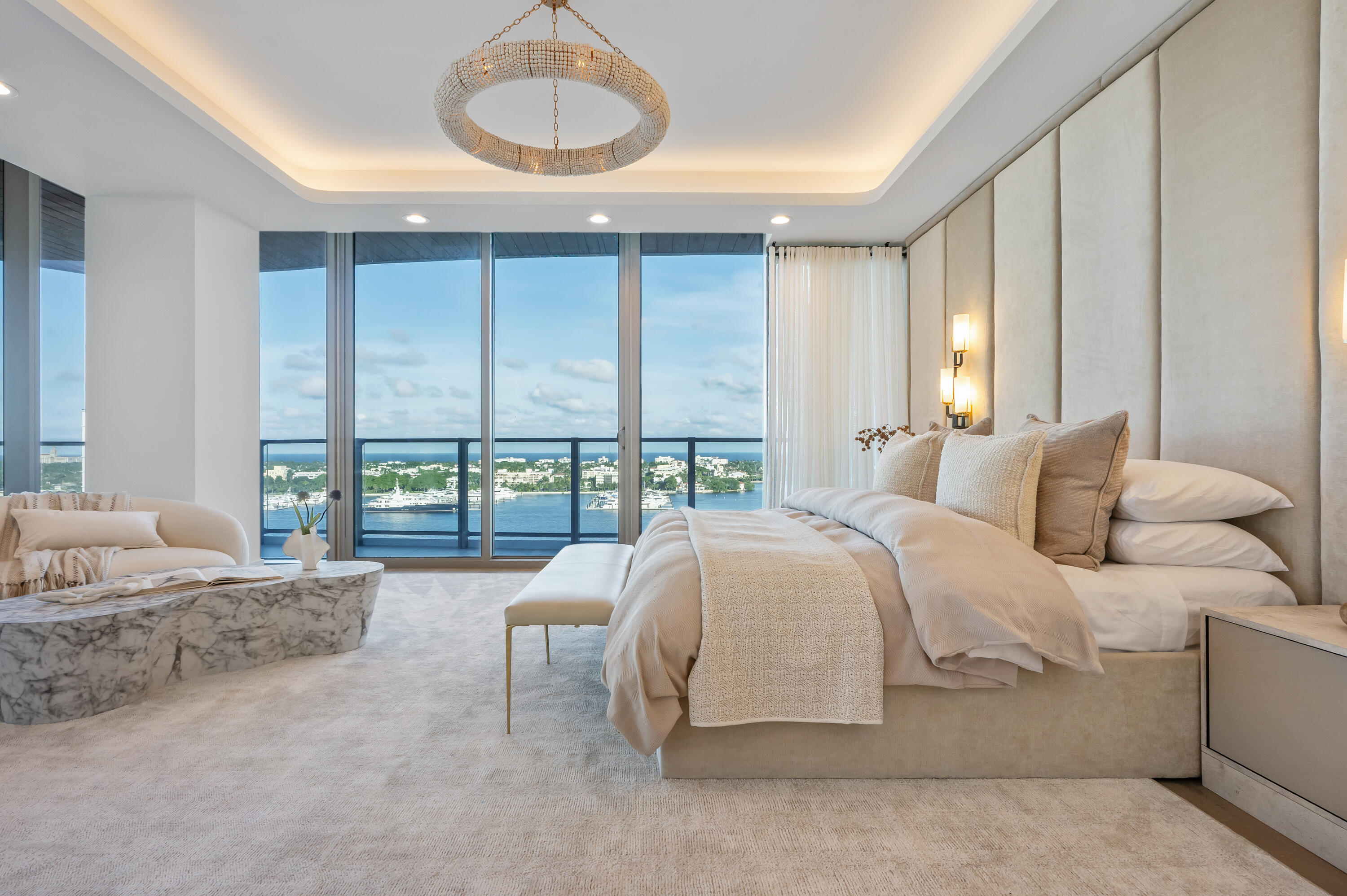 Contemporary bedroom with a king bed and floor-to-ceiling windows overlooking the water and waterfront homes.