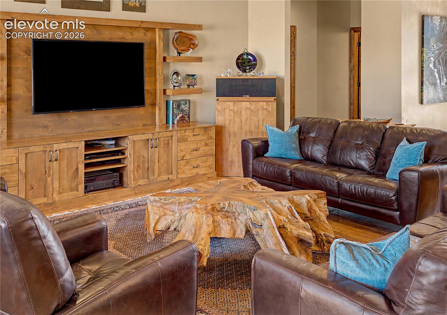 Living room with built-in wood media cabinetry, leather sofas, and a sculptural live-edge coffee table.