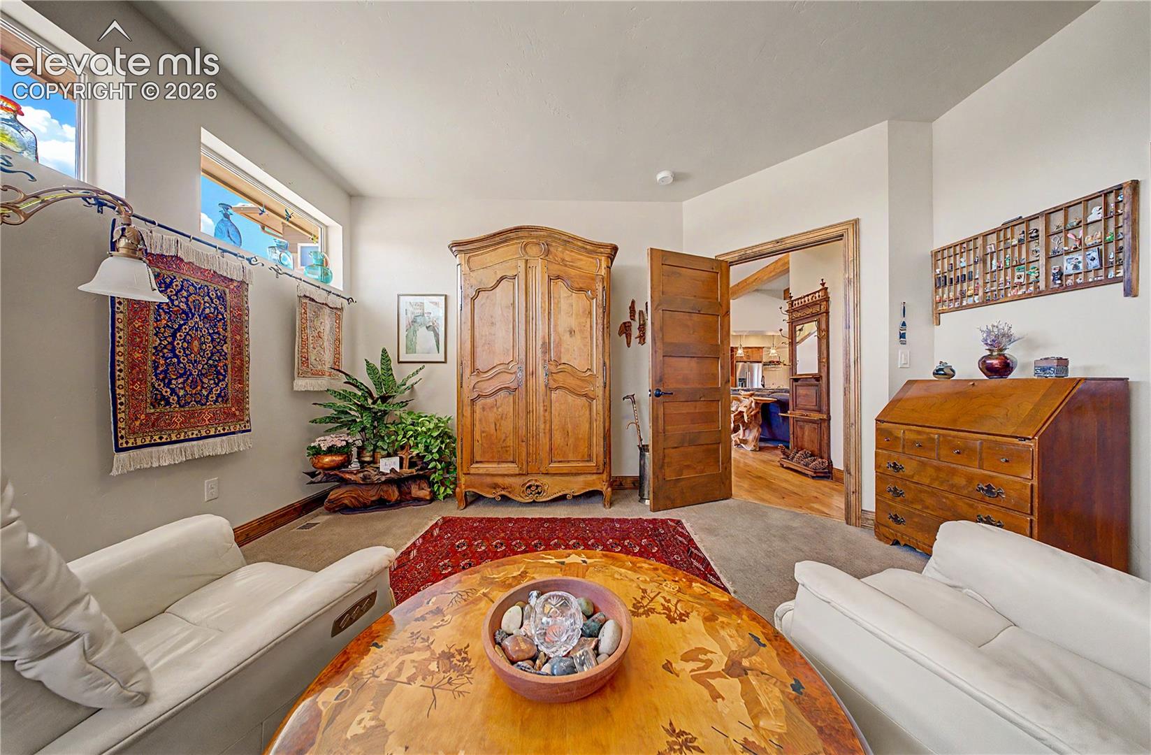 Living room with white sofas, patterned rugs, and ornate wooden furniture.