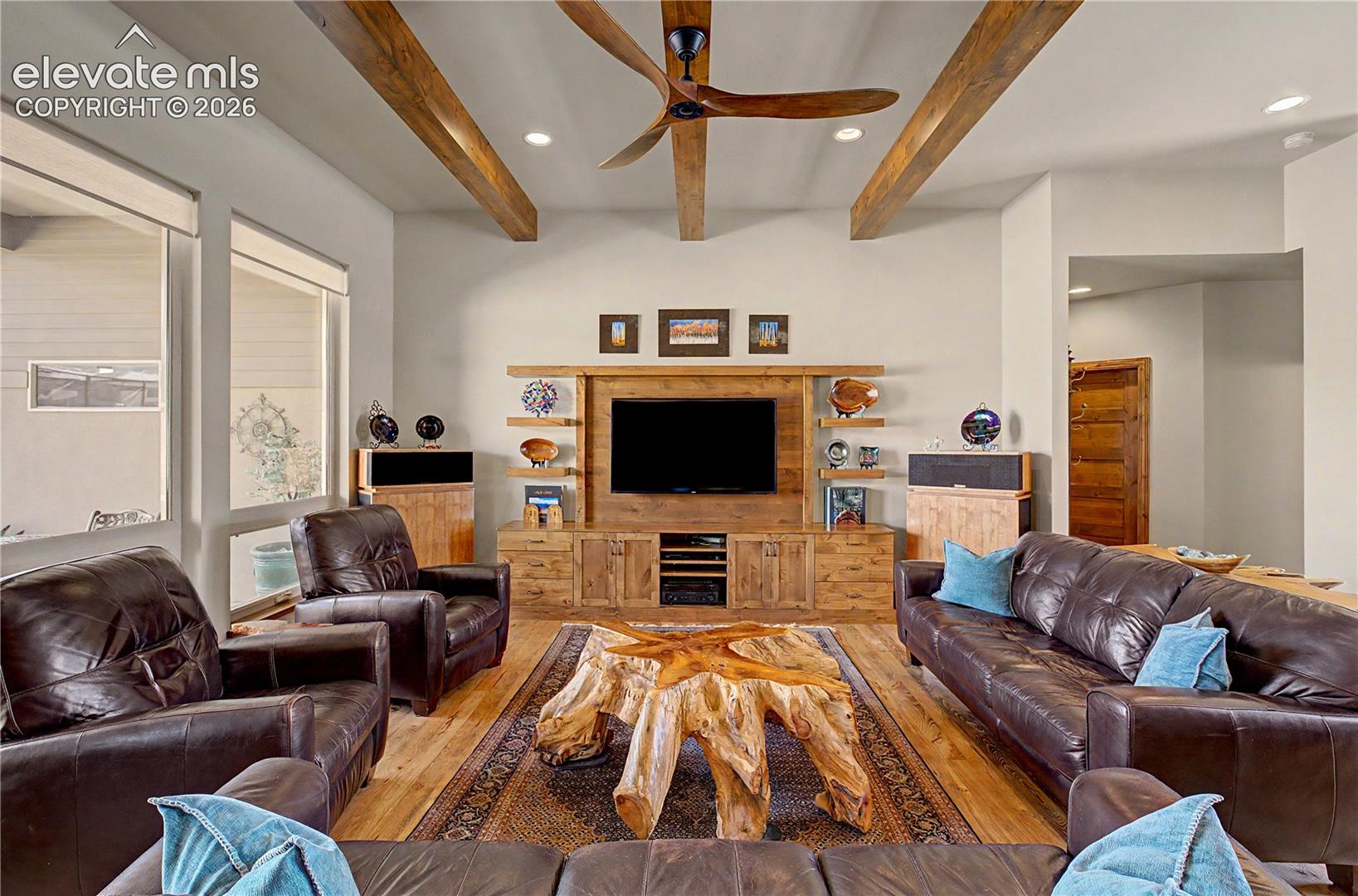 Living room with exposed wood beams, leather seating, and a rustic live-edge coffee table.