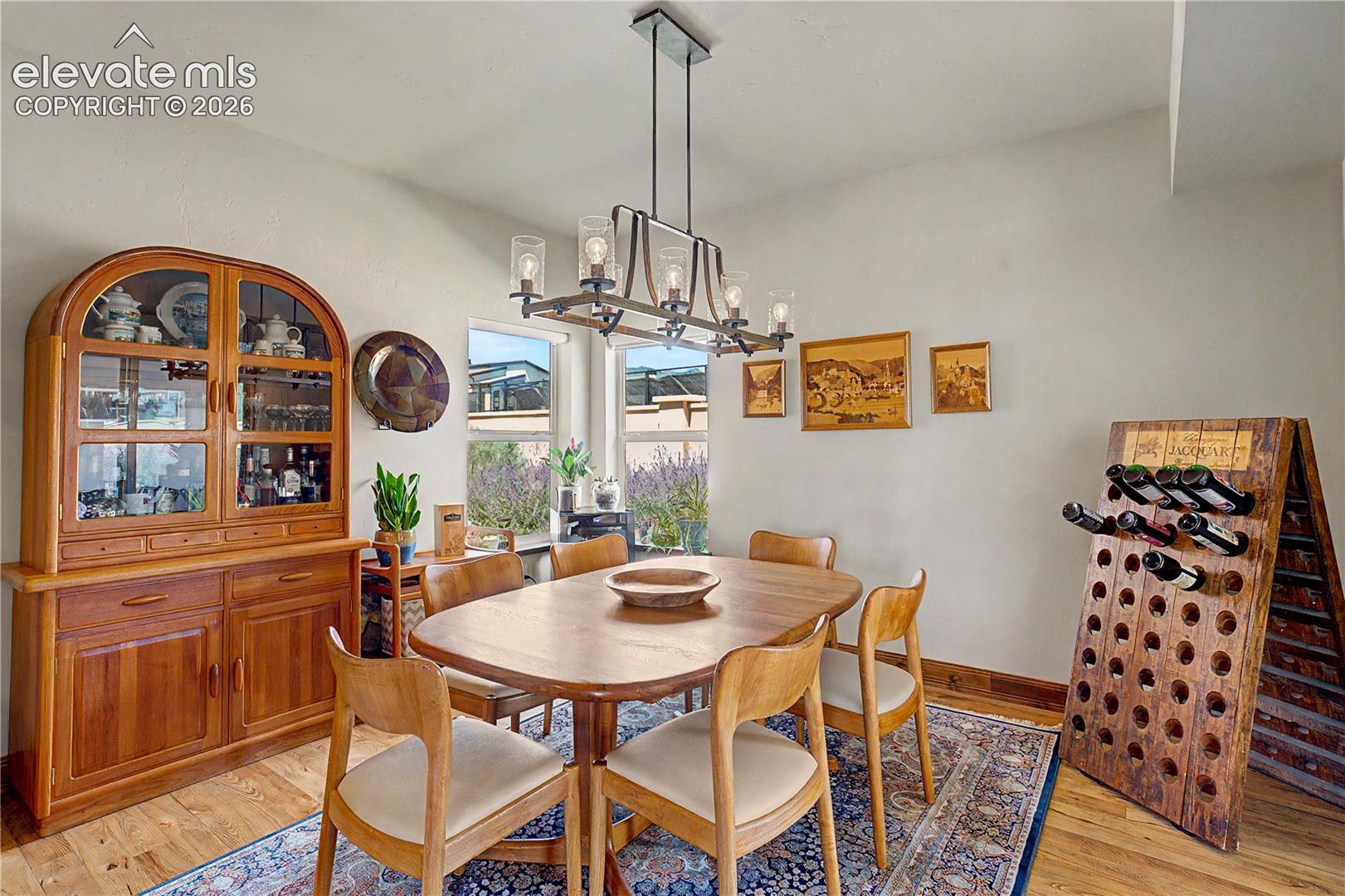 Dining room with a wooden table, china cabinet, wine rack, and modern chandelier.