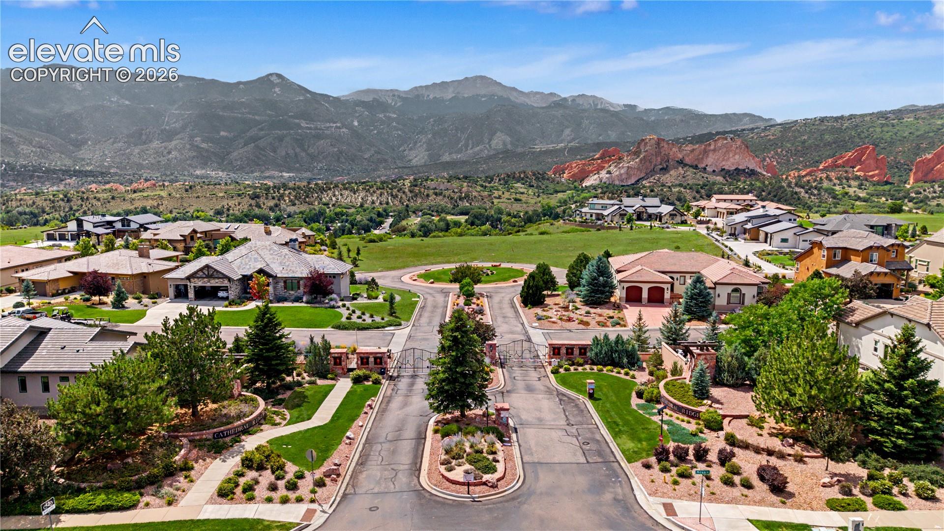 Gated community with landscaped streets and homes beneath mountain and red rock views.