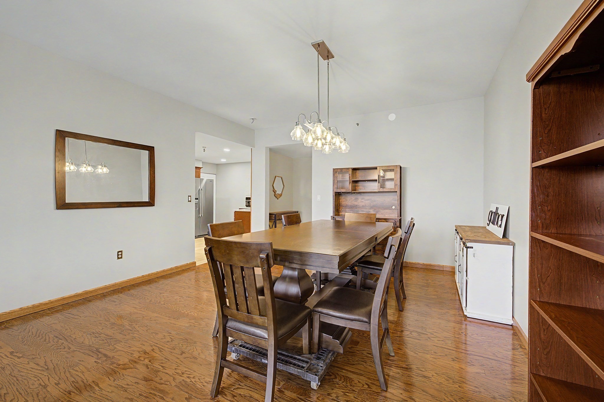 Dining room with a large wooden table, pendant chandelier, and hardwood floors.