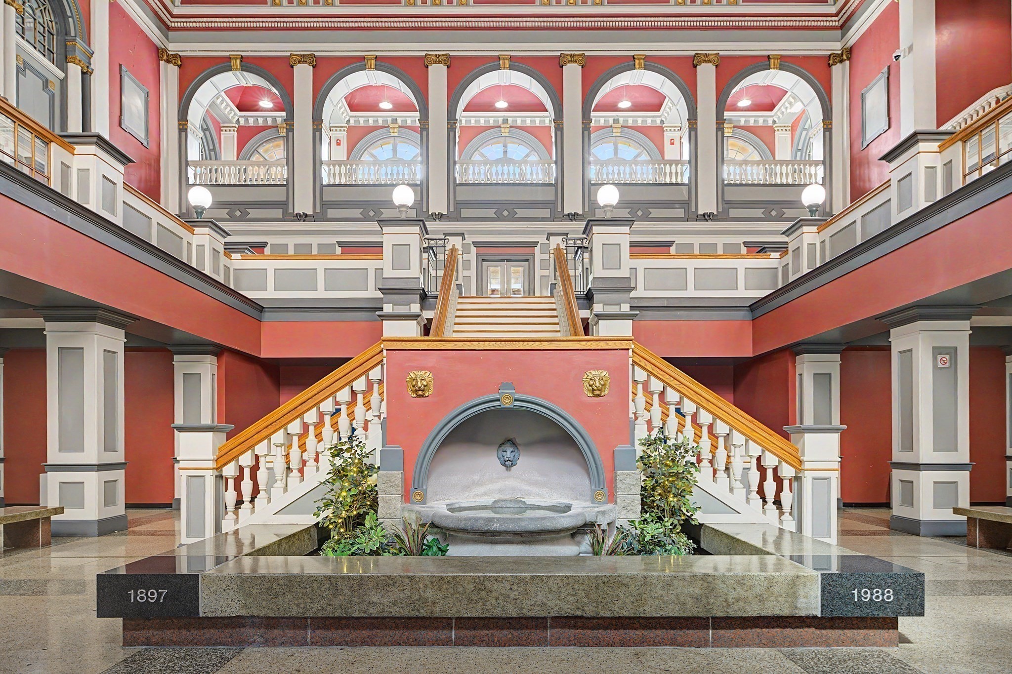 Grand lobby with a central fountain, sweeping staircase, and ornate arched balcony.