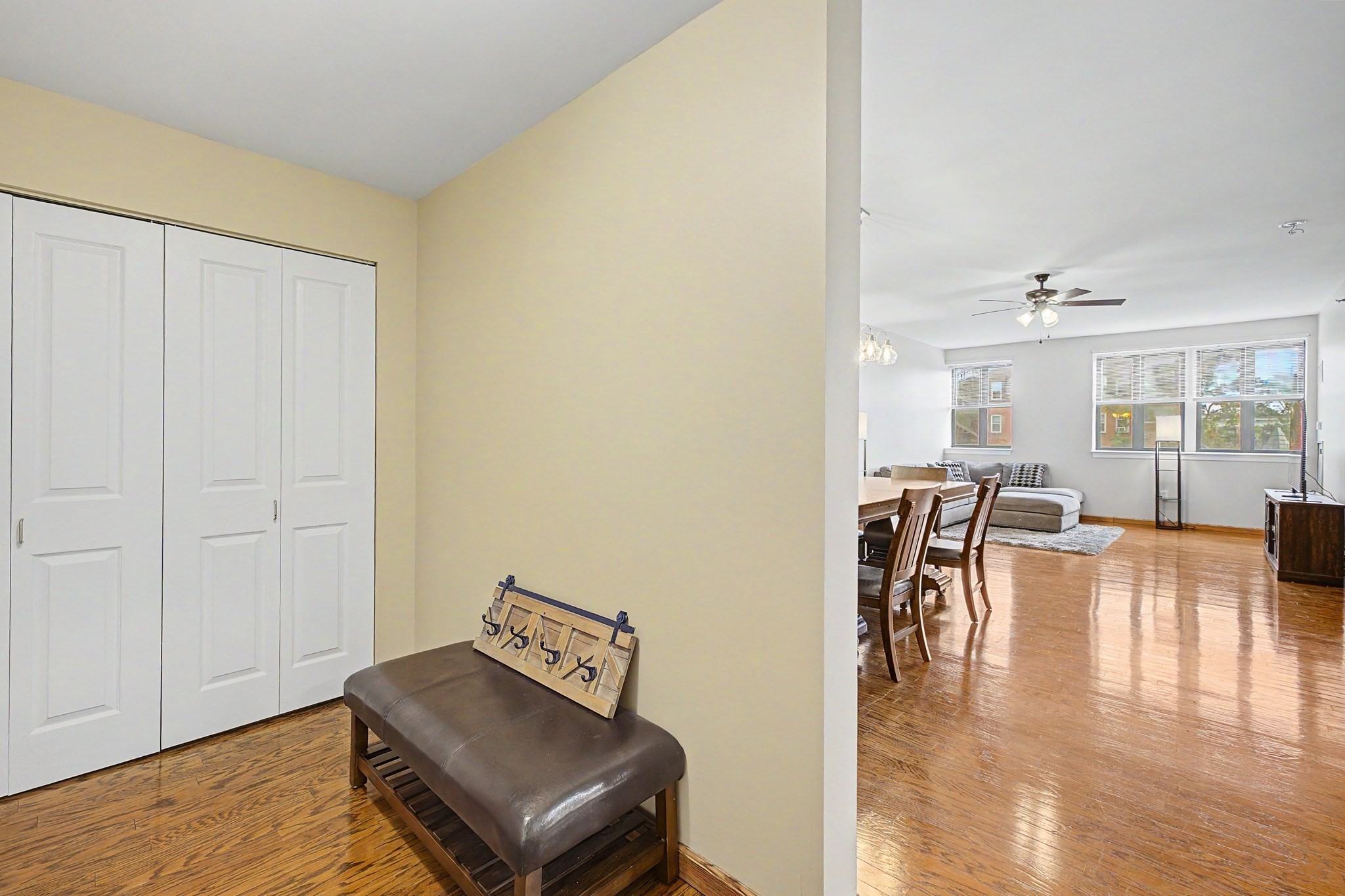 Entryway with a leather bench and coat rack opens onto a bright living and dining area.