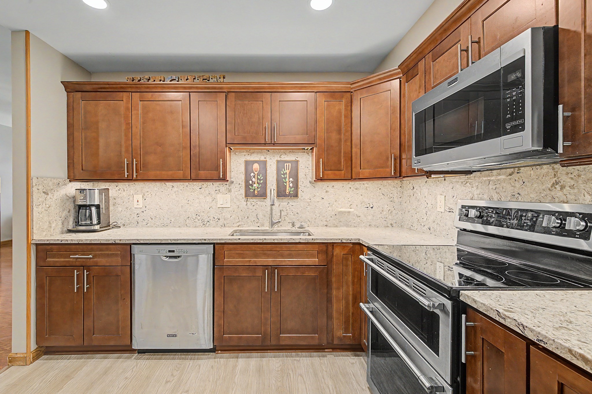 Kitchen with warm wood cabinets, light stone counters, and stainless steel appliances.