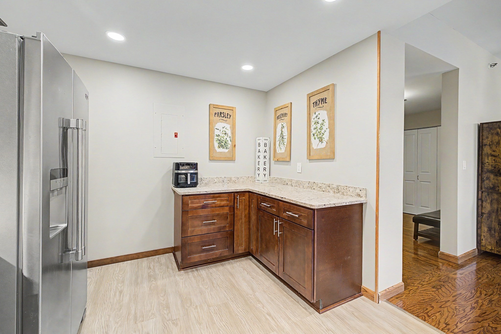 Kitchen with dark wood cabinets, stone countertops, and a stainless steel refrigerator.