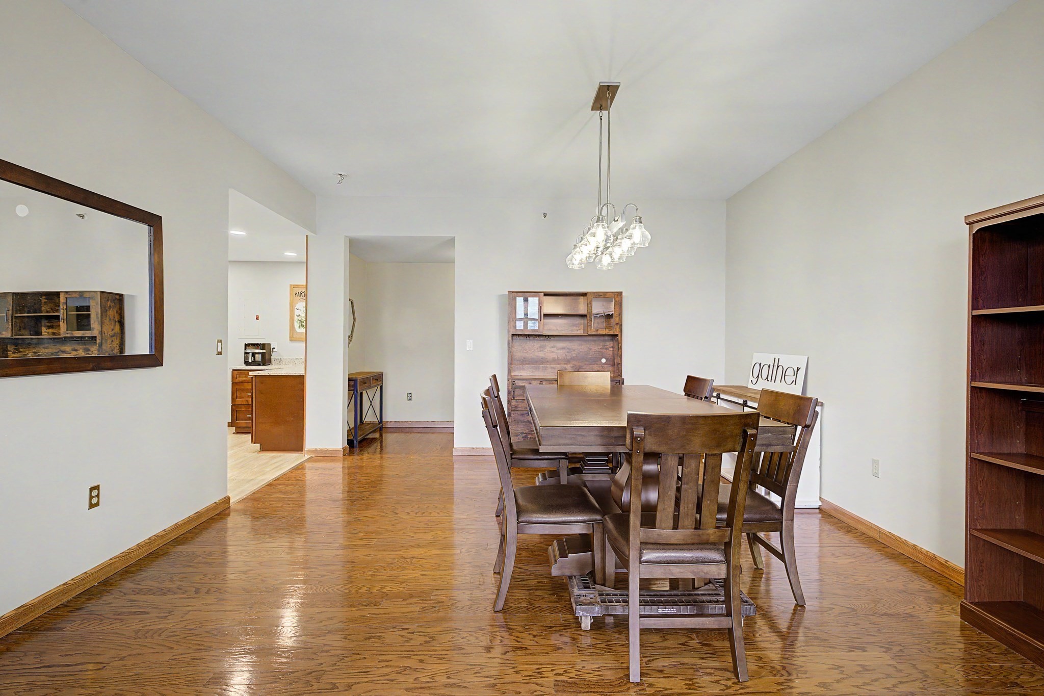 Dining room with a long wooden table, parquet floors, and built-in shelving.