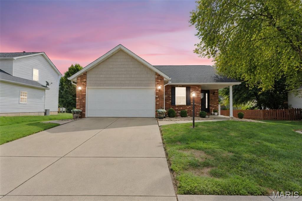 Single-story brick-and-shingle home with a two-car garage and broad driveway at dusk.