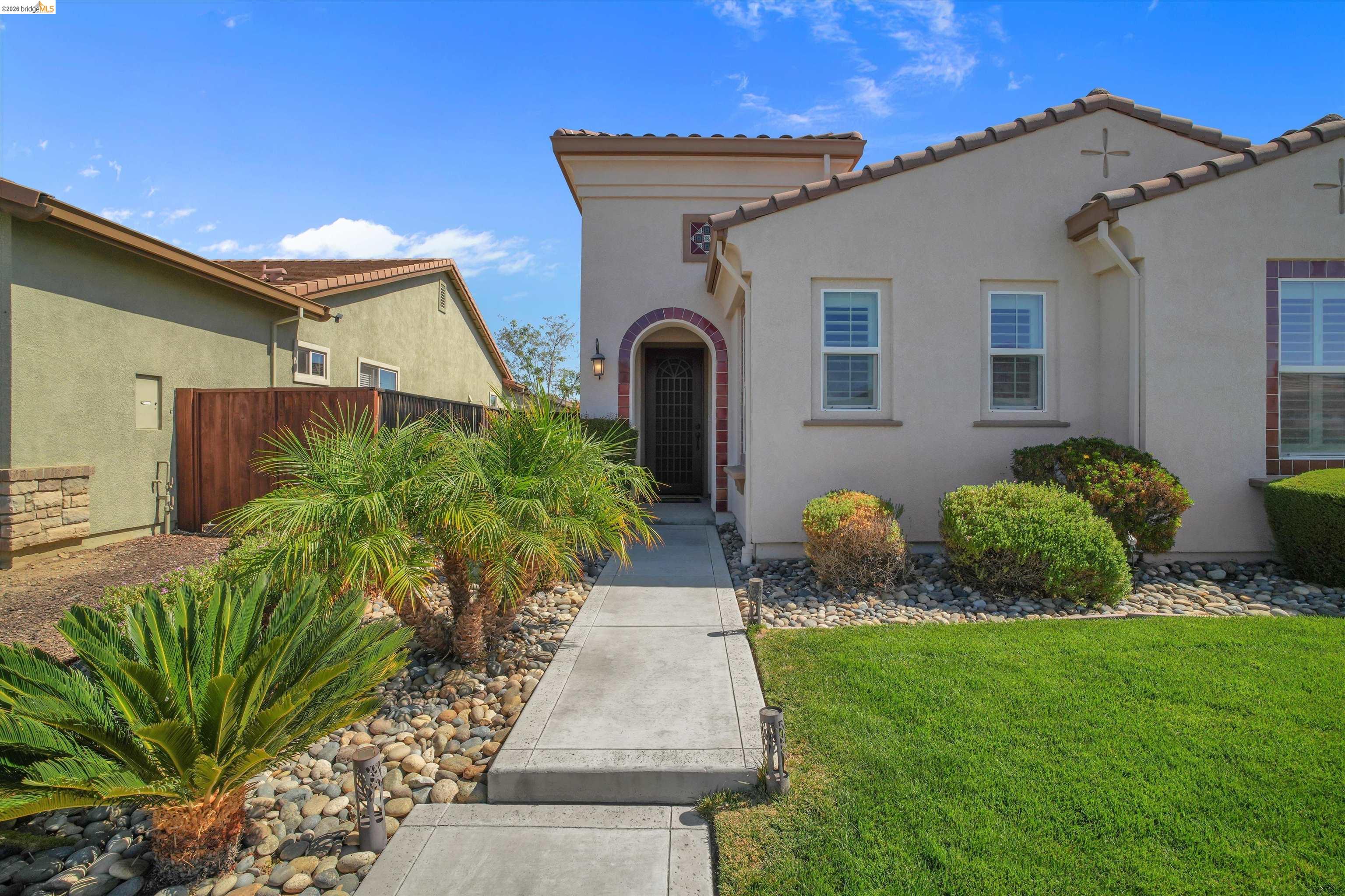 Home exterior with an arched front entry, landscaped walkway, and tiled roof.