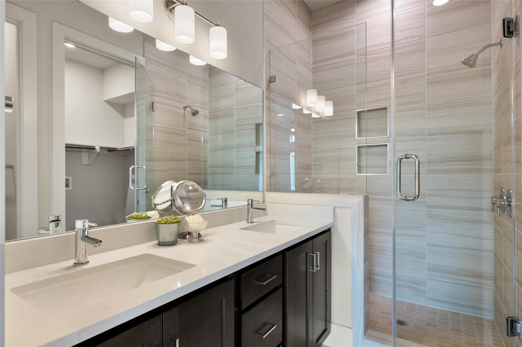 Modern bathroom with a double-sink vanity and glass-enclosed tiled shower.