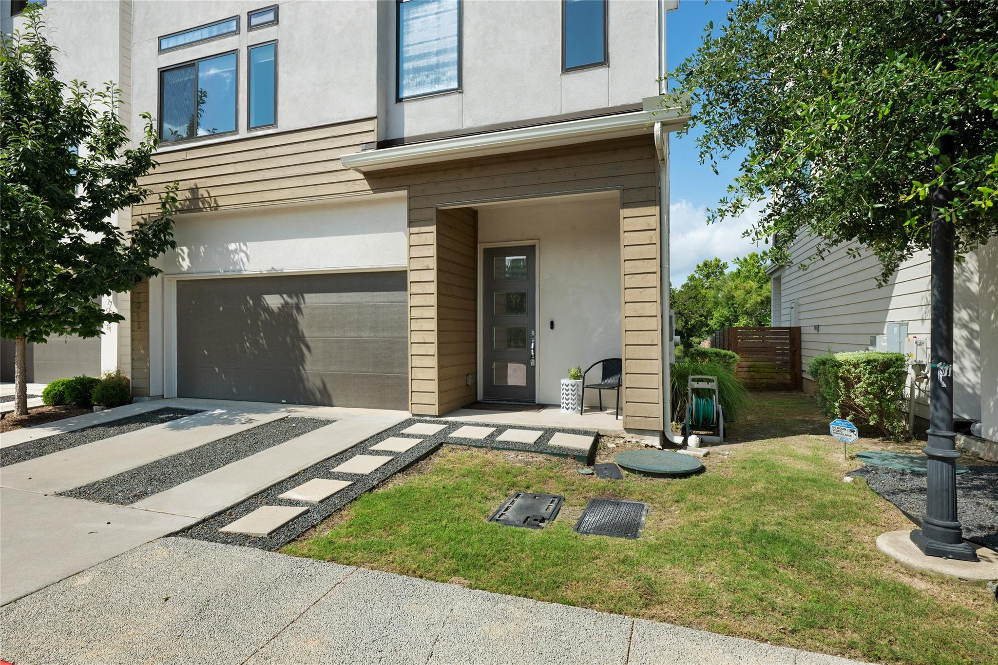 Modern two-story home with a gray garage door, recessed entry, and concrete paths across the front lawn.
