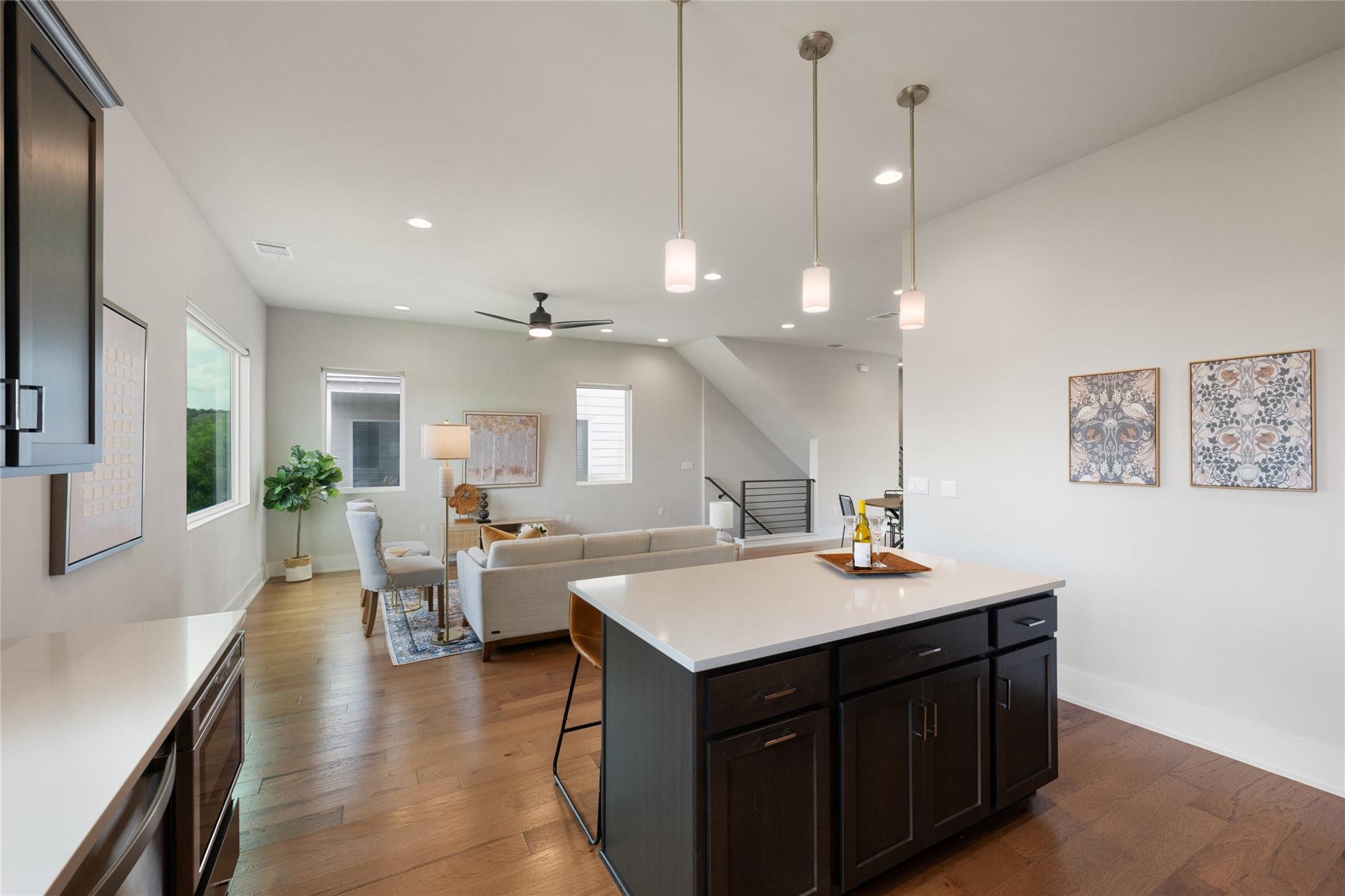 Open-plan kitchen with a large dark-wood island overlooking a staged living area.