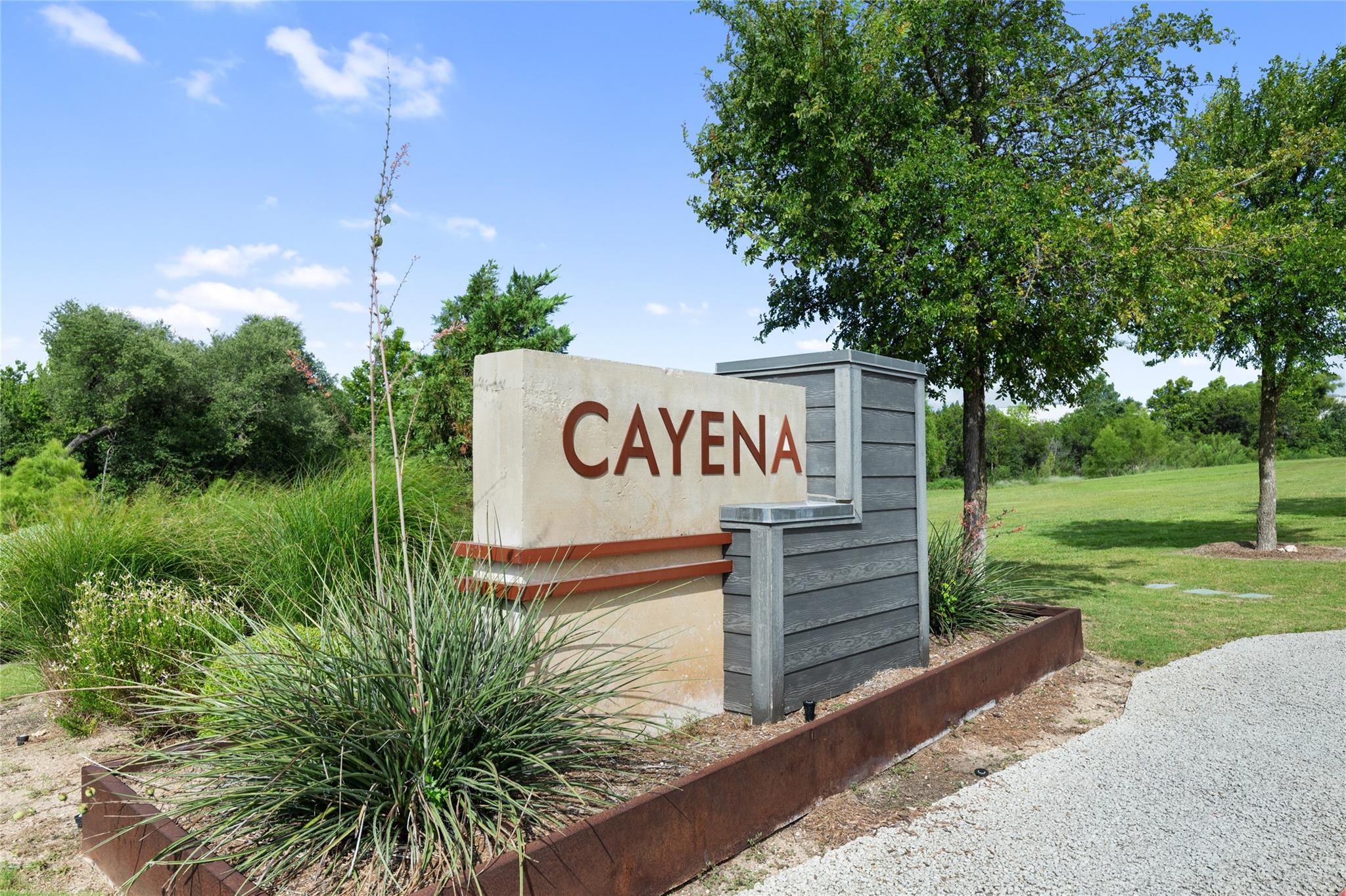 Cayena neighborhood entrance sign beside landscaped grounds and a gravel drive.