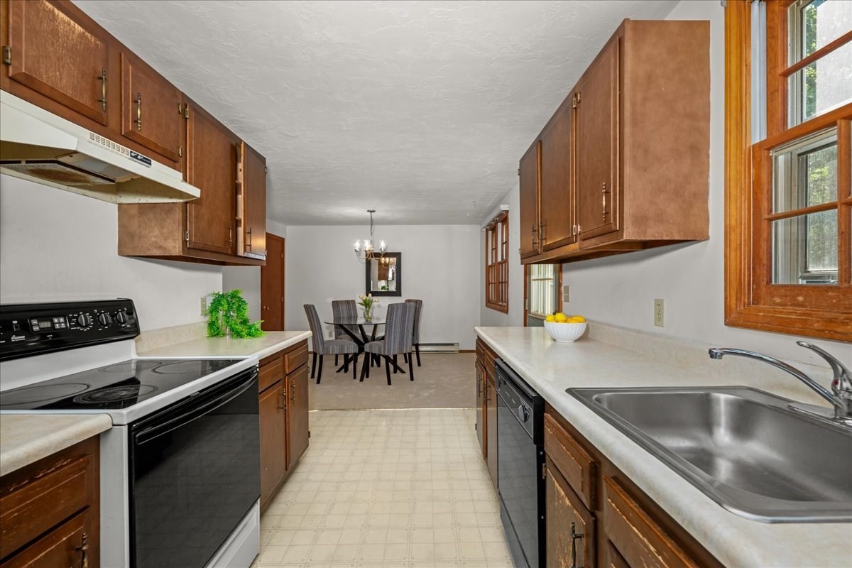 Kitchen with wood cabinets, white counters, a double sink, and a dining area at the far end.