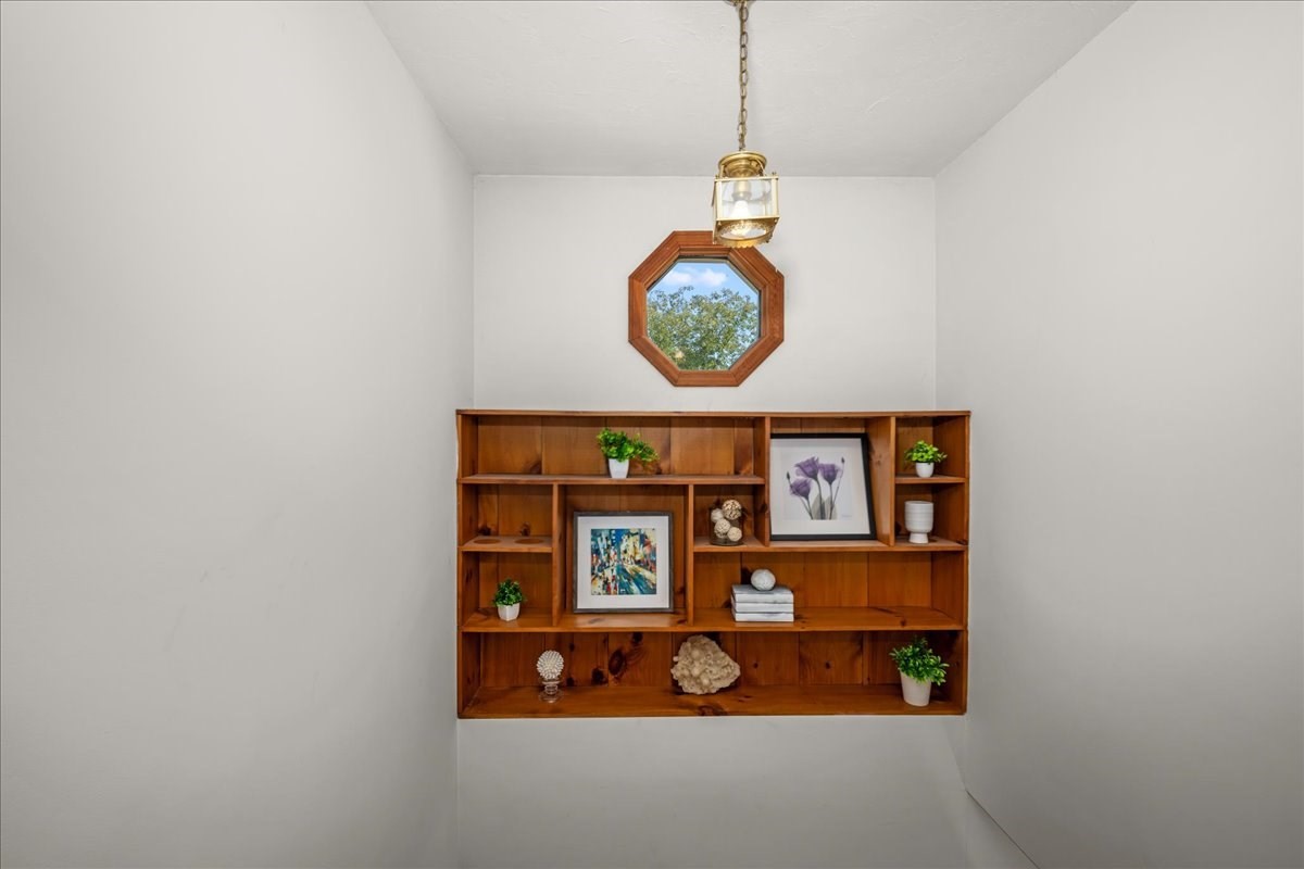 Built-in wooden display shelves beneath an octagonal window and brass pendant light.