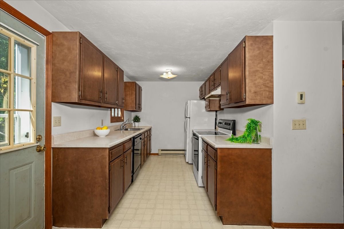 Kitchen with dark wood cabinets, pale counters, and white appliances.
