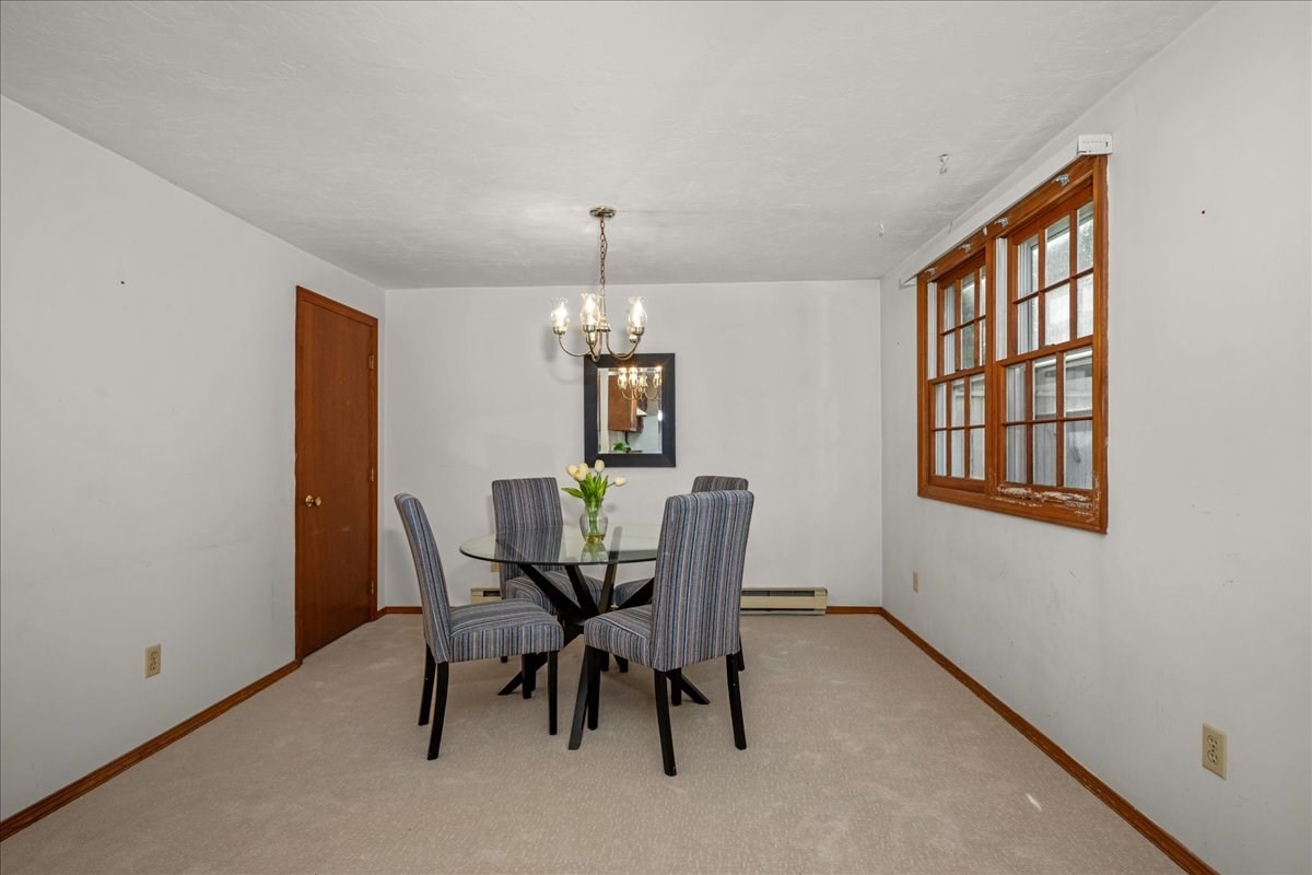 Dining room with a glass table, four striped chairs, and wood-trimmed windows.