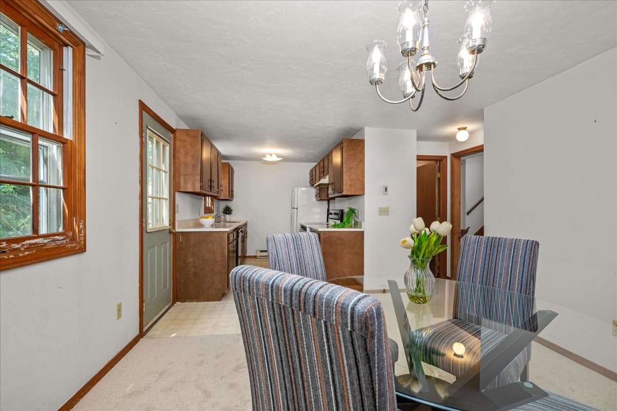 Dining area with a glass table, striped chairs, and tulips beside the kitchen.