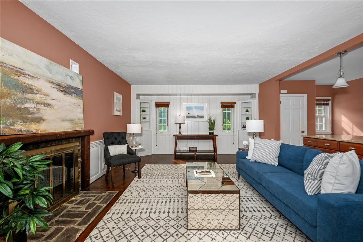 Living room with a stone fireplace, blue sofa, and patterned rug.