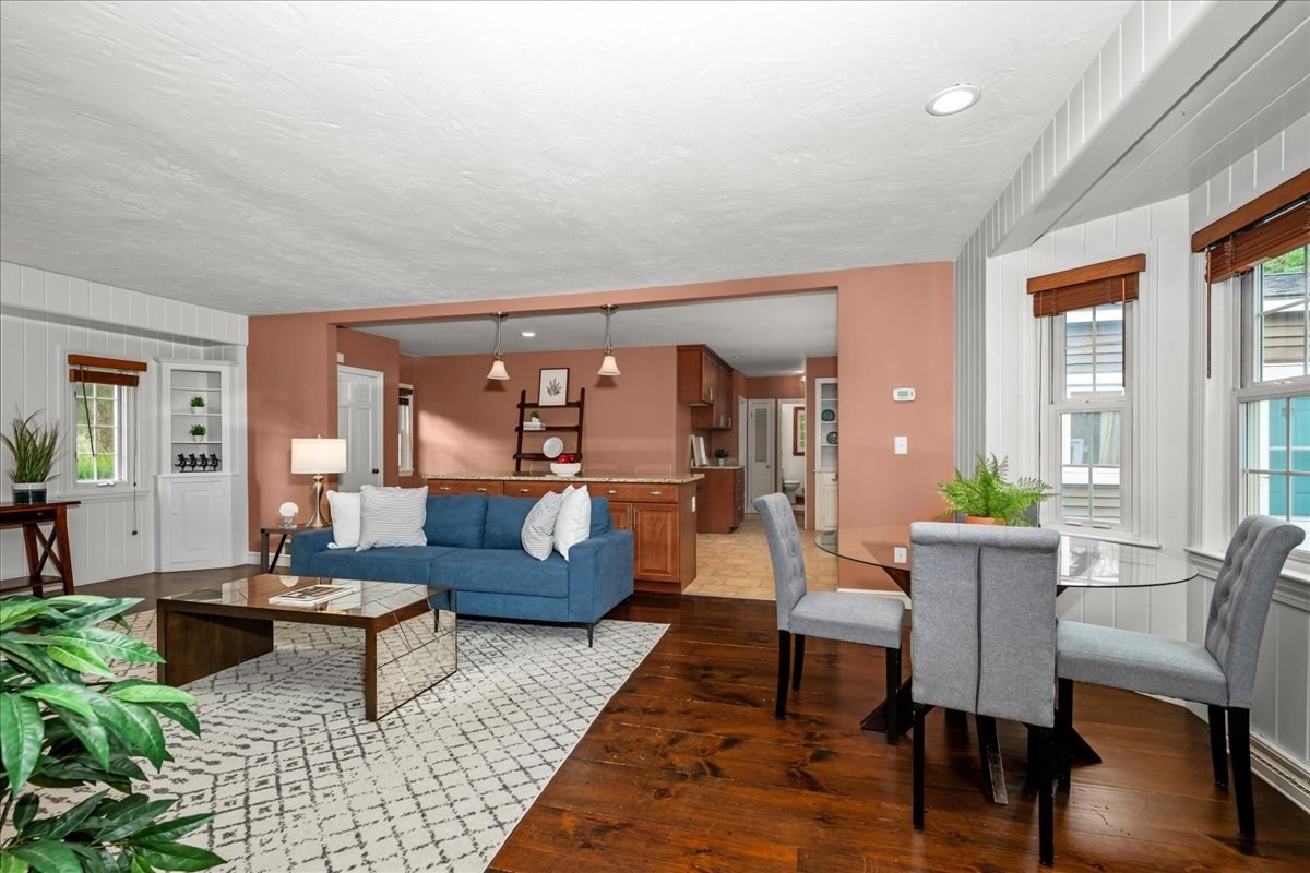 Open living and dining area with a blue sofa, glass dining table, and dark wood floors.