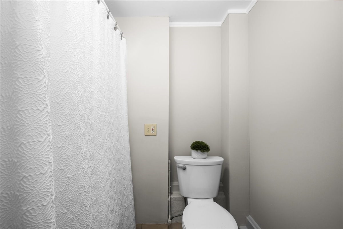 Compact bathroom with a white toilet and textured shower curtain.