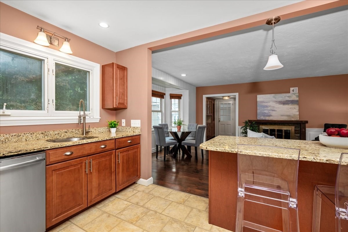 Kitchen with granite island, warm wood cabinets, and an adjoining dining and living area.