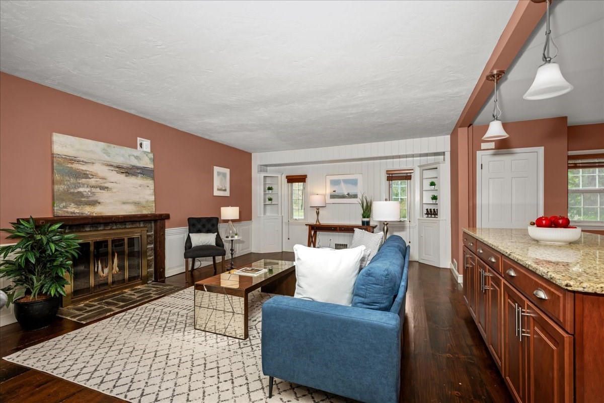 Living room with a blue sofa, stone fireplace, patterned rug, and built-in shelving.