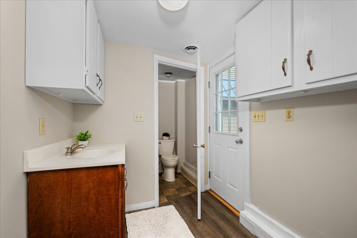 Bathroom with a dark wood vanity, toilet alcove, and glazed exterior door.