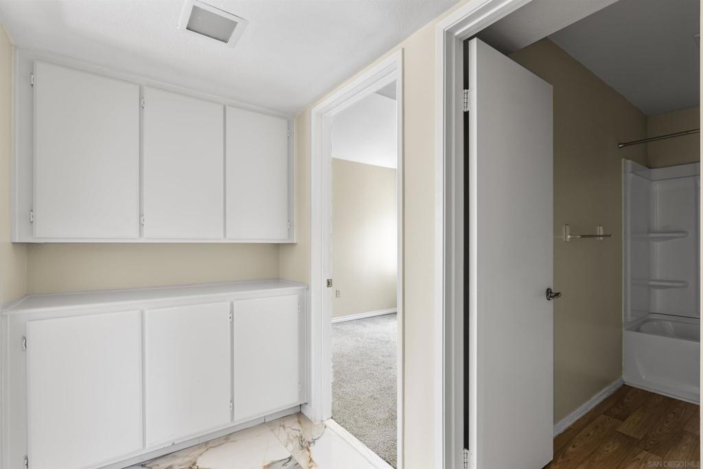 Hallway with built-in white cabinets and doorways to a carpeted room and bathroom.