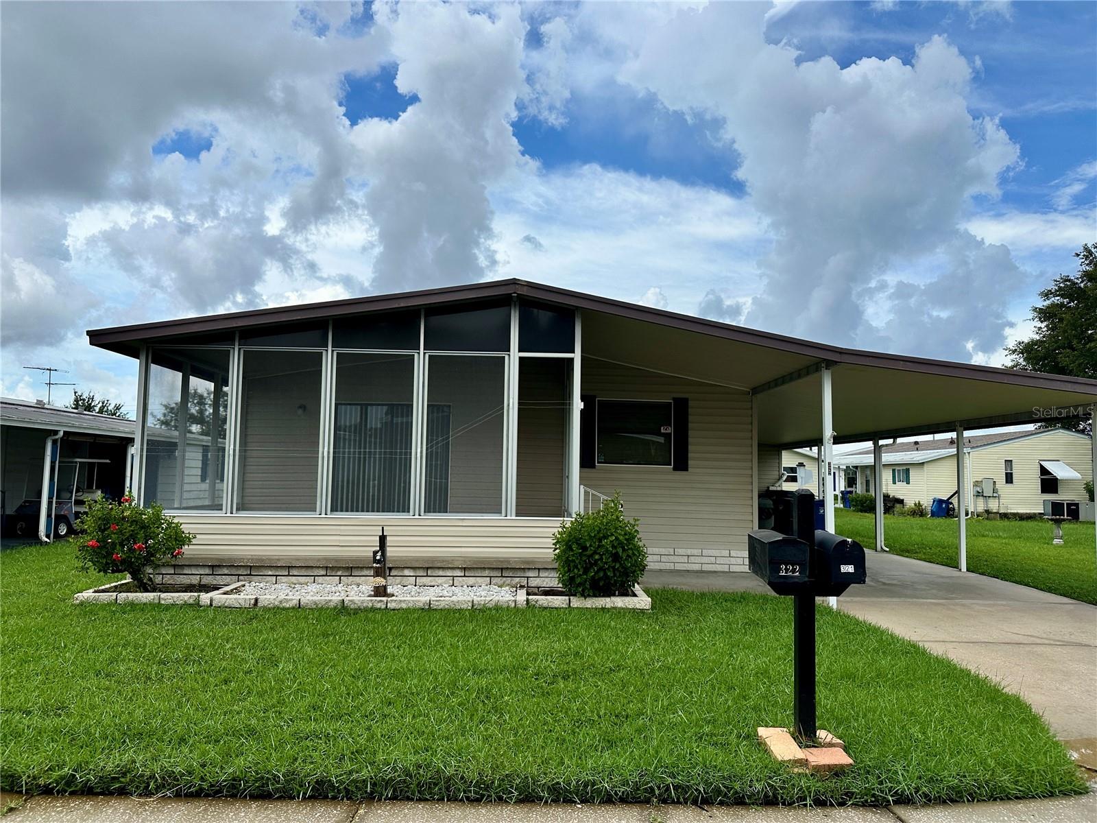 Single-story home with a screened front porch, wide carport, and mailbox numbered 322.