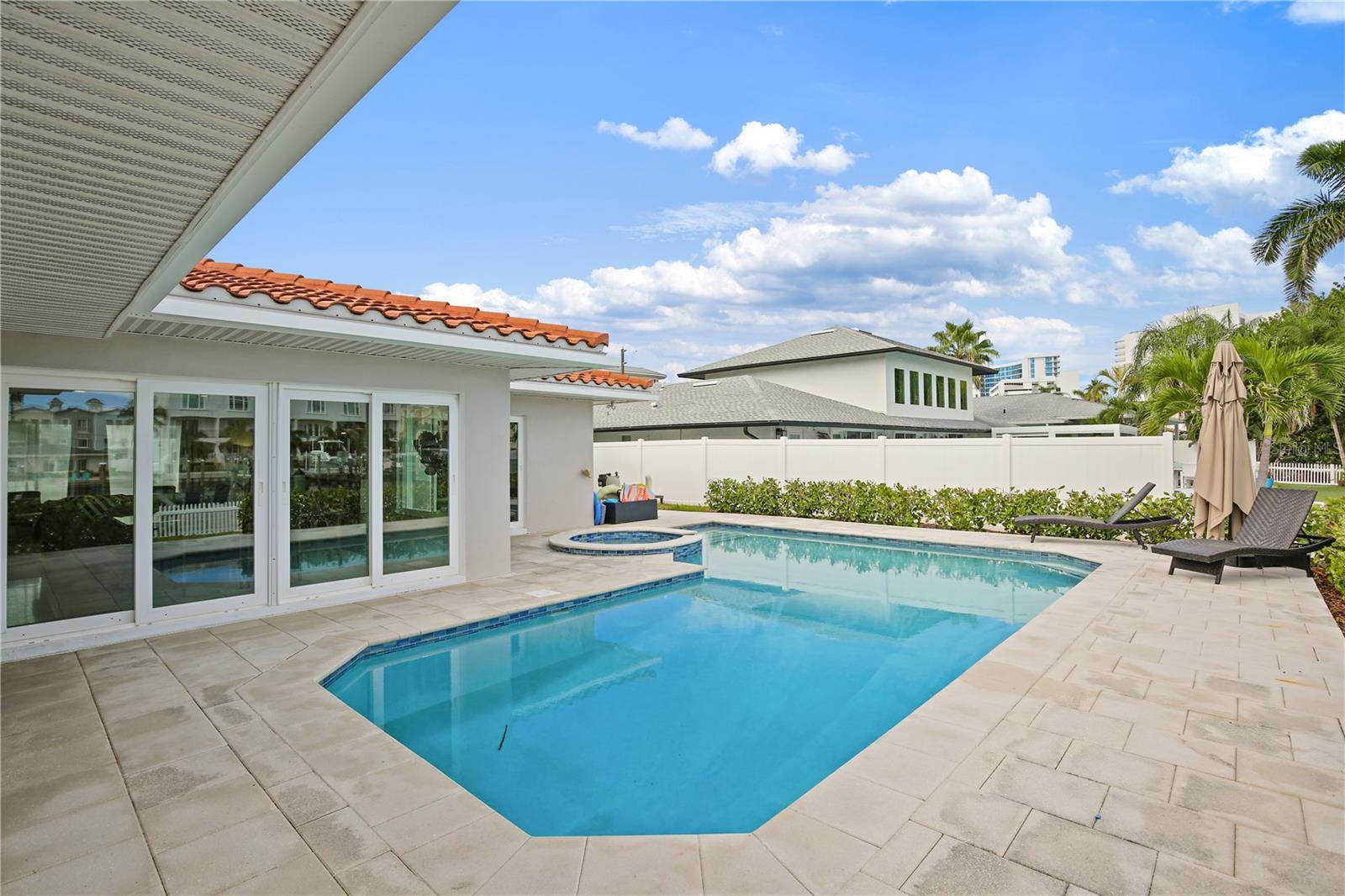 Backyard swimming pool with an attached circular spa, stone patio, and poolside lounge chairs.