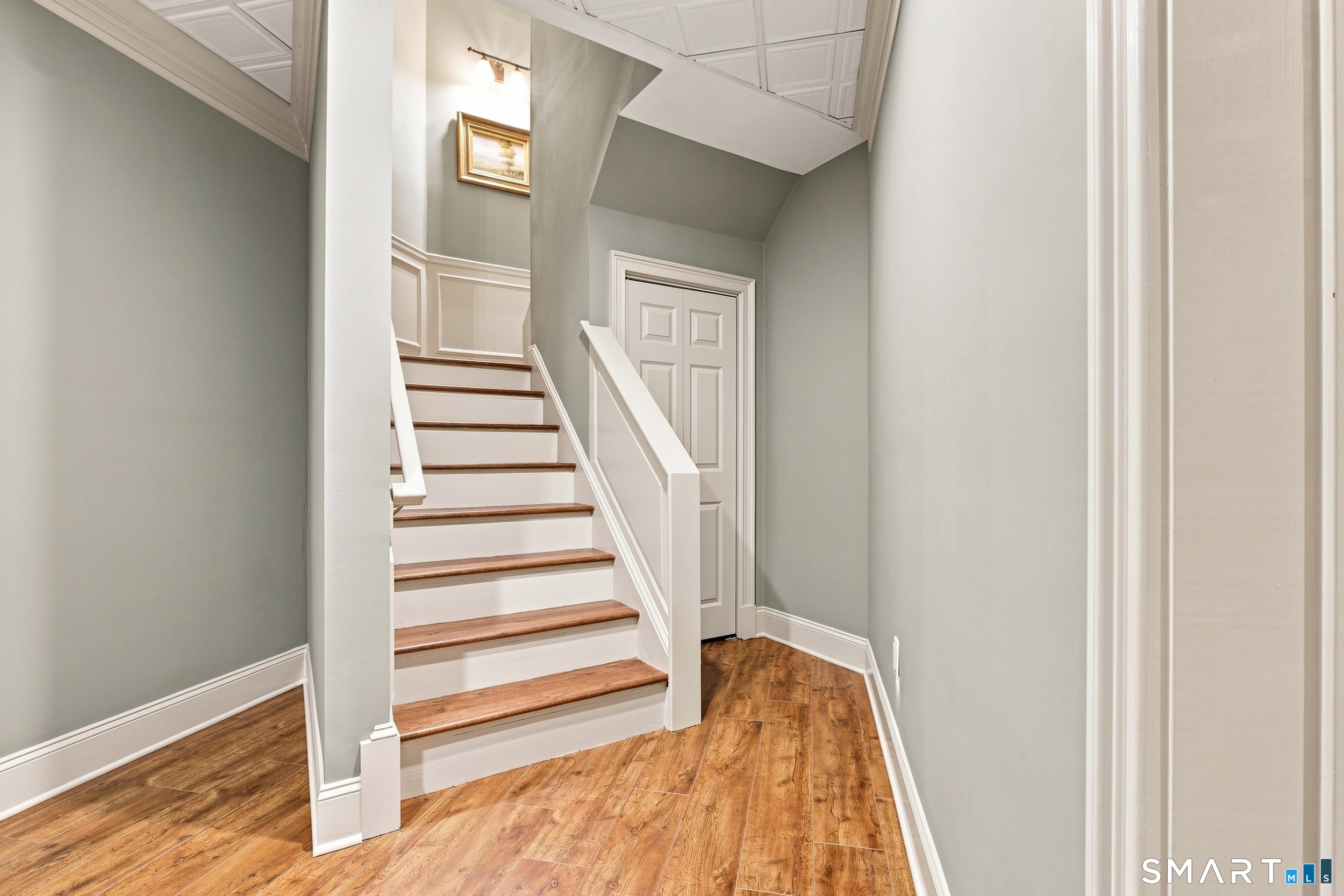 Interior hallway with wood-look flooring and a white staircase with wooden treads.