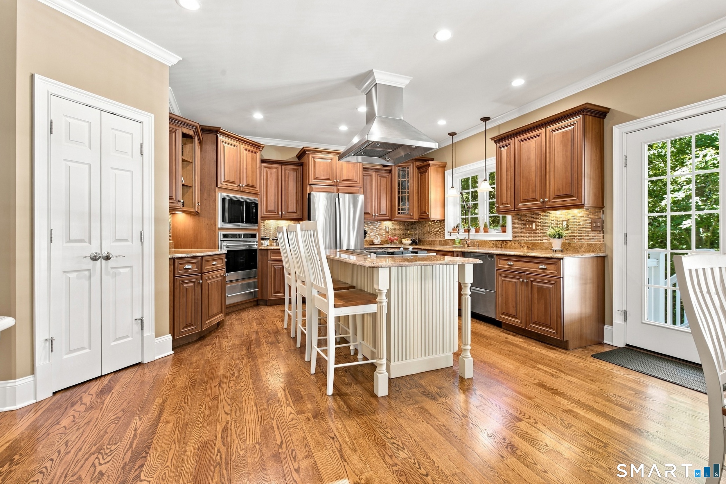 Kitchen with dark wood cabinets, a large island, stainless steel appliances, and hardwood floors.