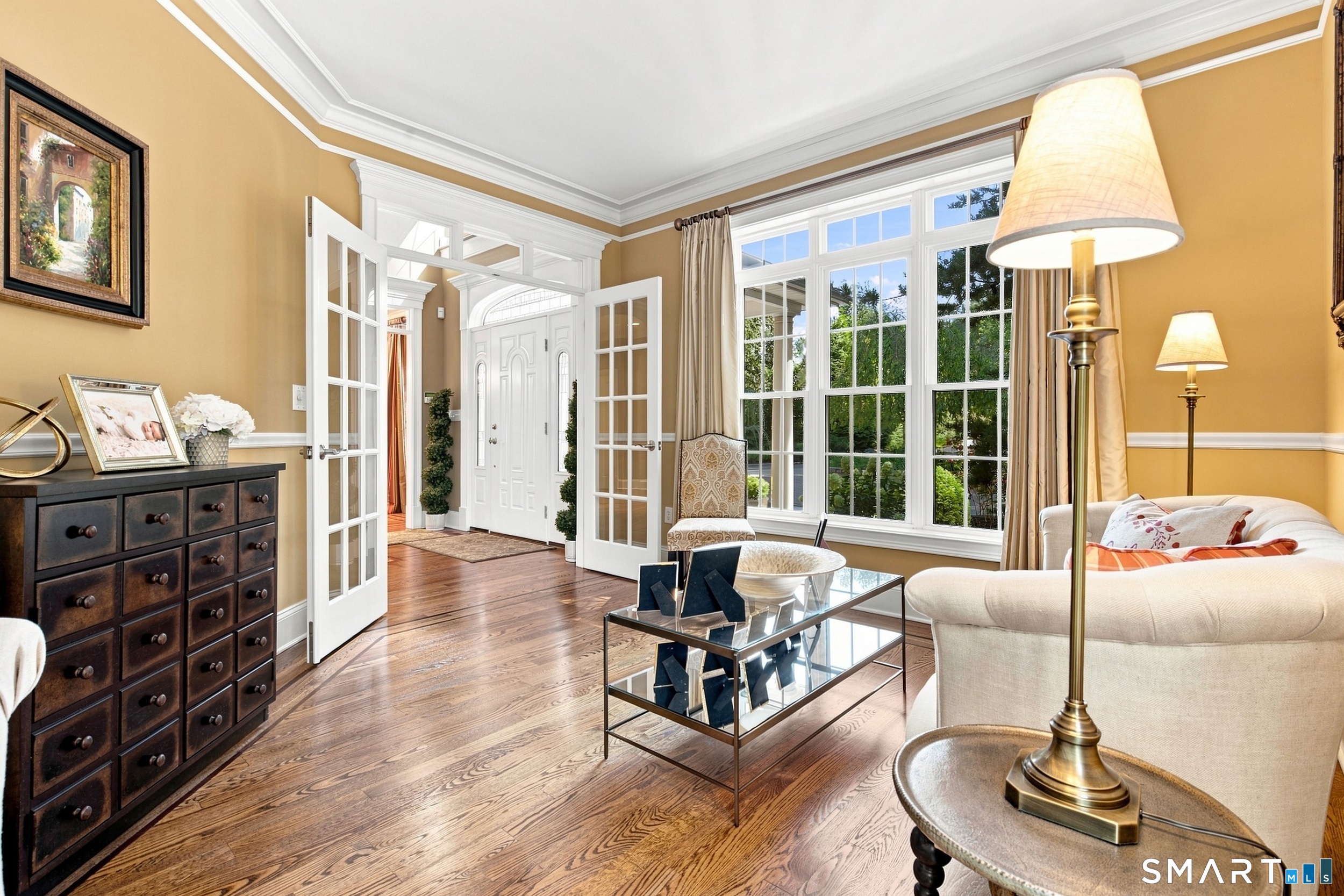Living room with hardwood floors, tall windows, French doors, and a white sofa.