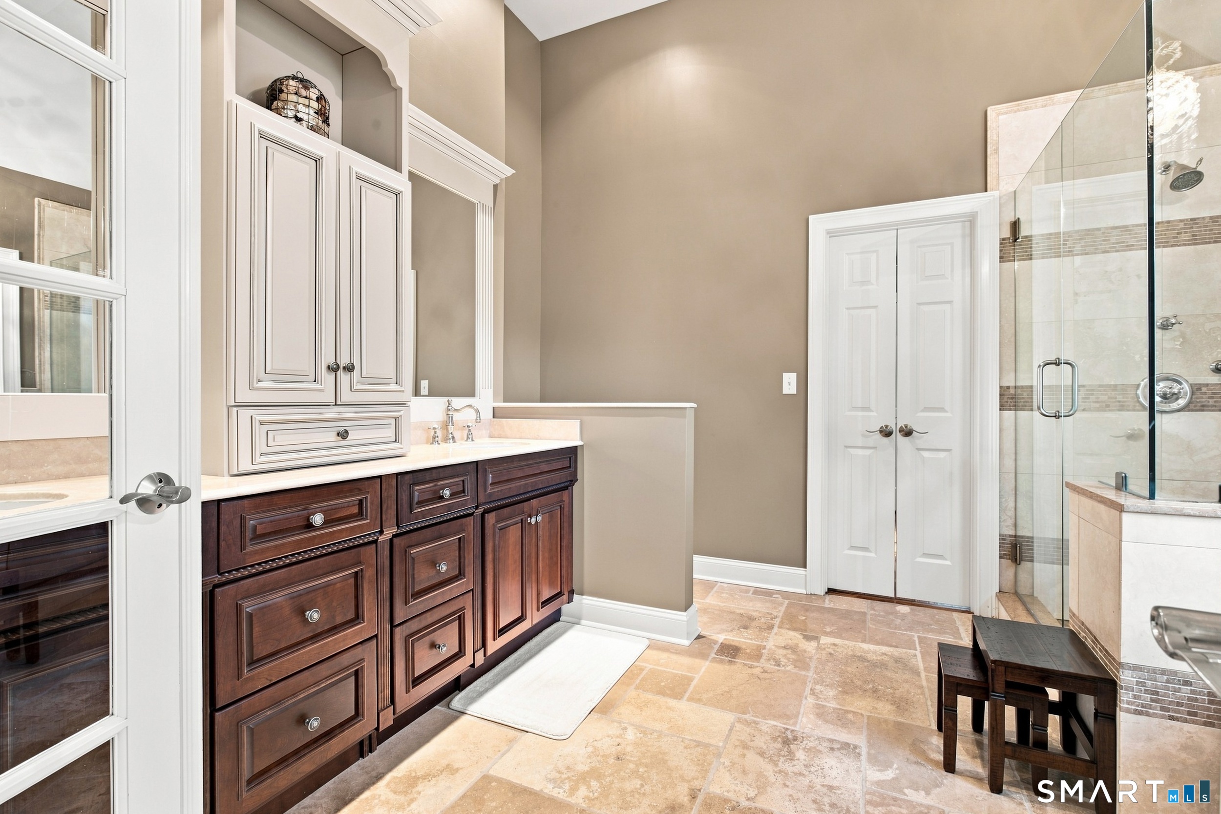 Bathroom with a dark wood double vanity and glass-enclosed tiled shower.