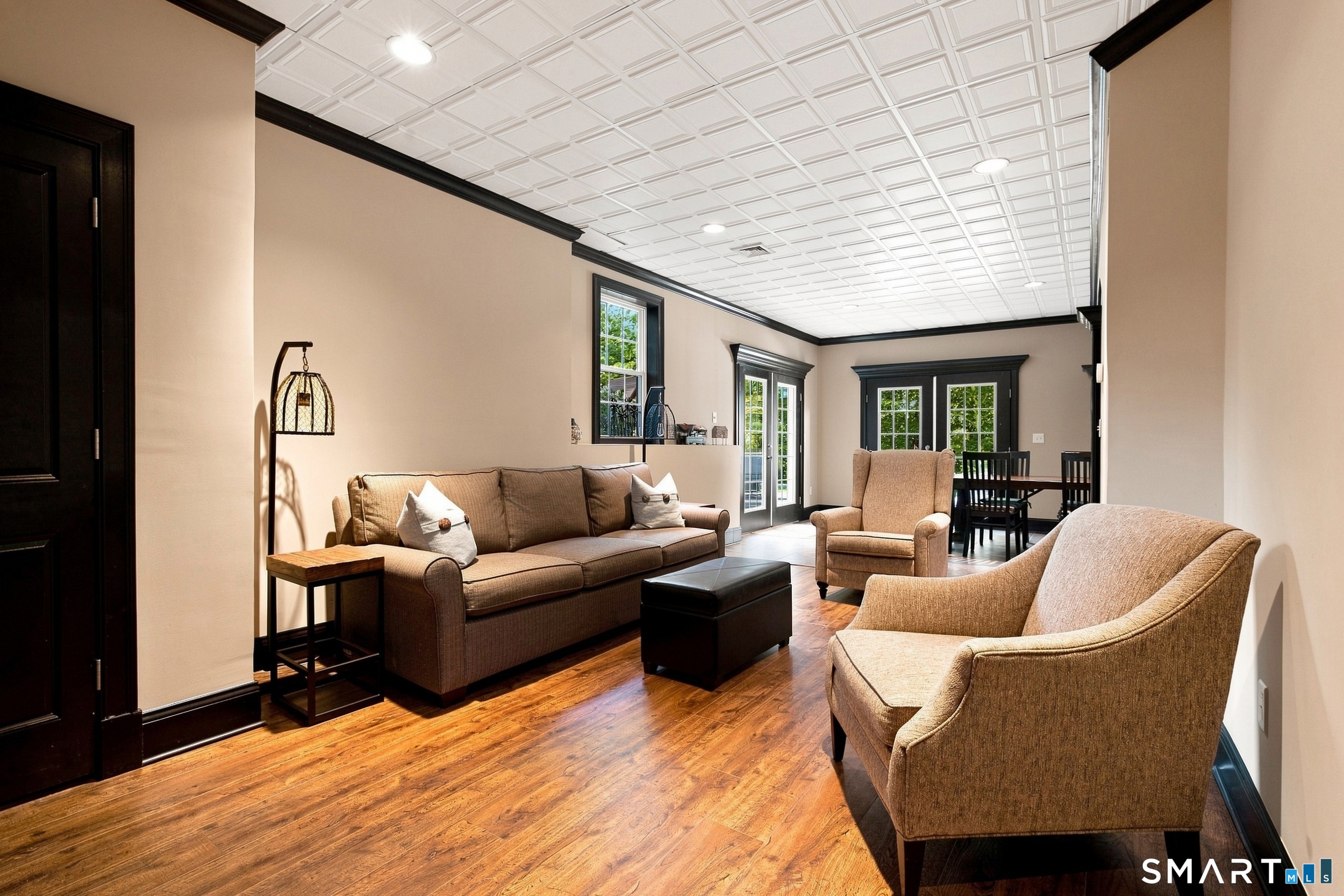 Furnished living room with hardwood floors, a brown sofa, and a coffered ceiling.