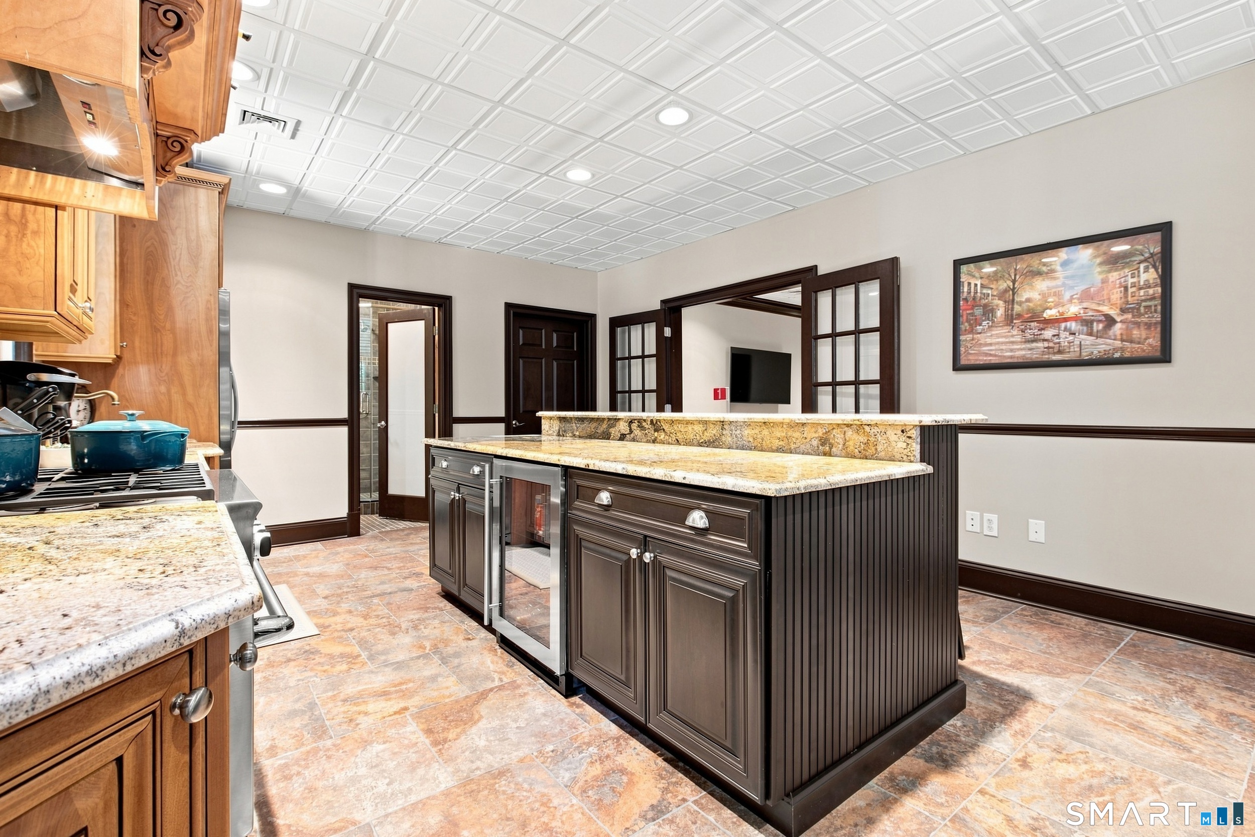 Kitchen with a large granite-topped island, wood cabinetry, and patterned tile floor.