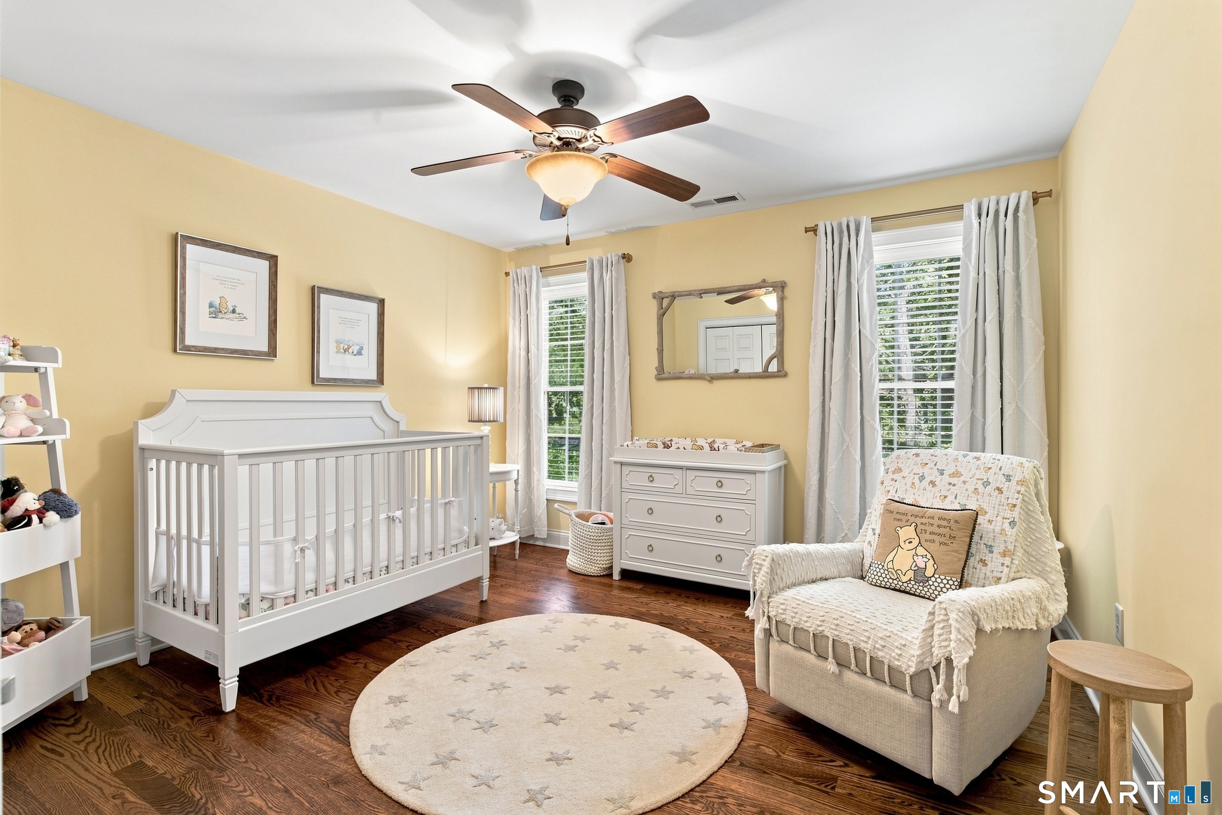 Nursery with a white crib, dresser, rocking chair, and round star-patterned rug.