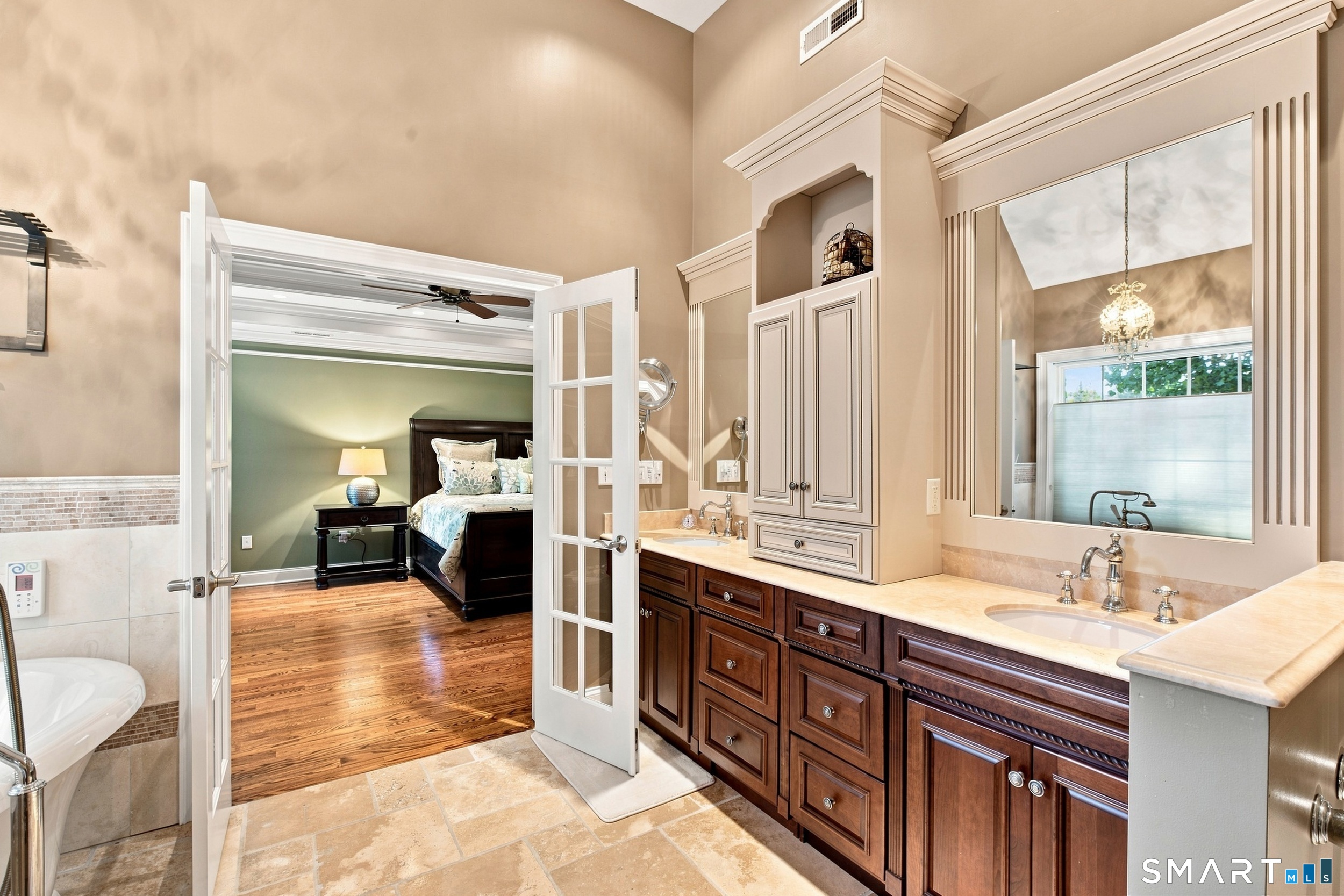 Bathroom with a dark wood double vanity and open French doors into a bedroom.